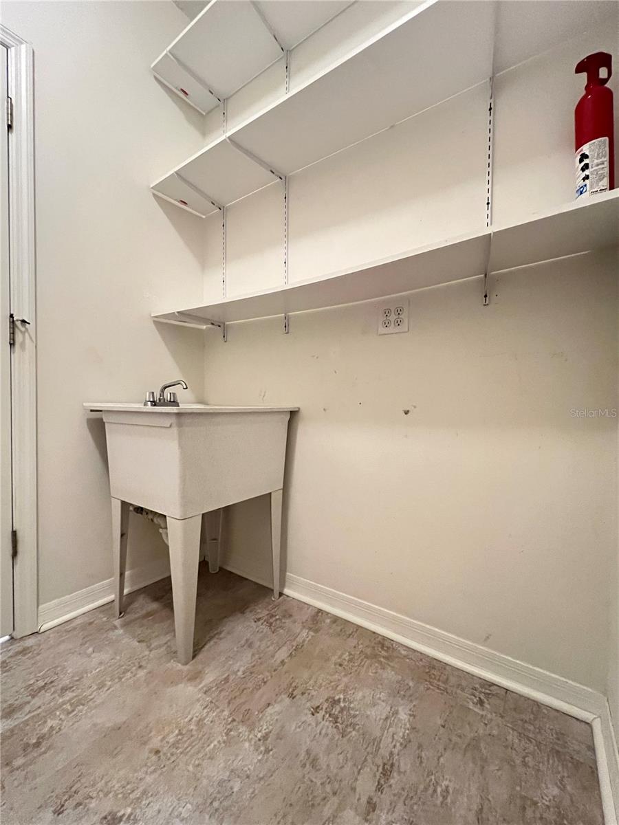 The laundry room has a utility sink and TON of shelving space!