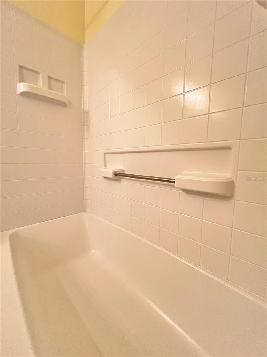 The second full bathroom has an oversized tub with grab bars, tile flooring, a newer toilet, and great cabinet space.