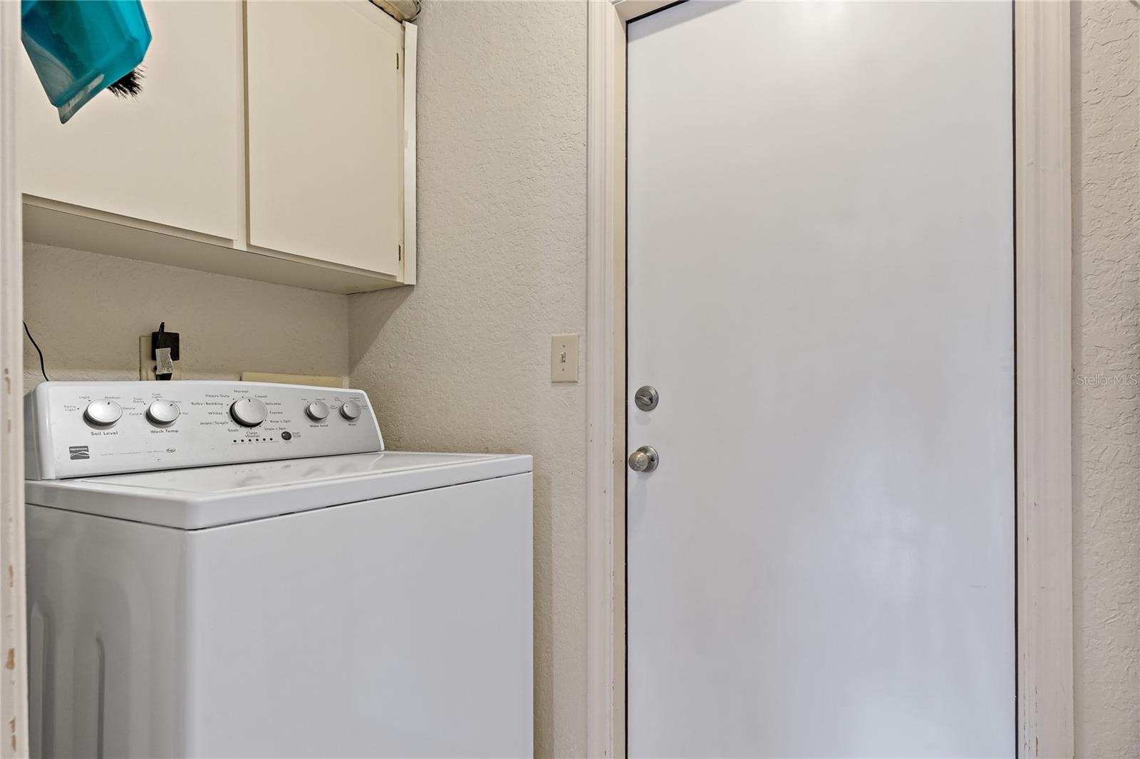 Laundry Room with Cabinet Storage above both washer and dryer, a pocket door to kitchen and Door into Garage