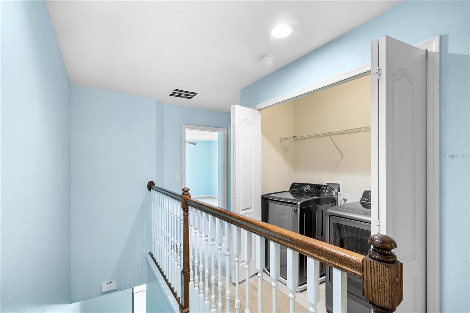 Top of the stairs, laundry and leading into the primary bedroom.