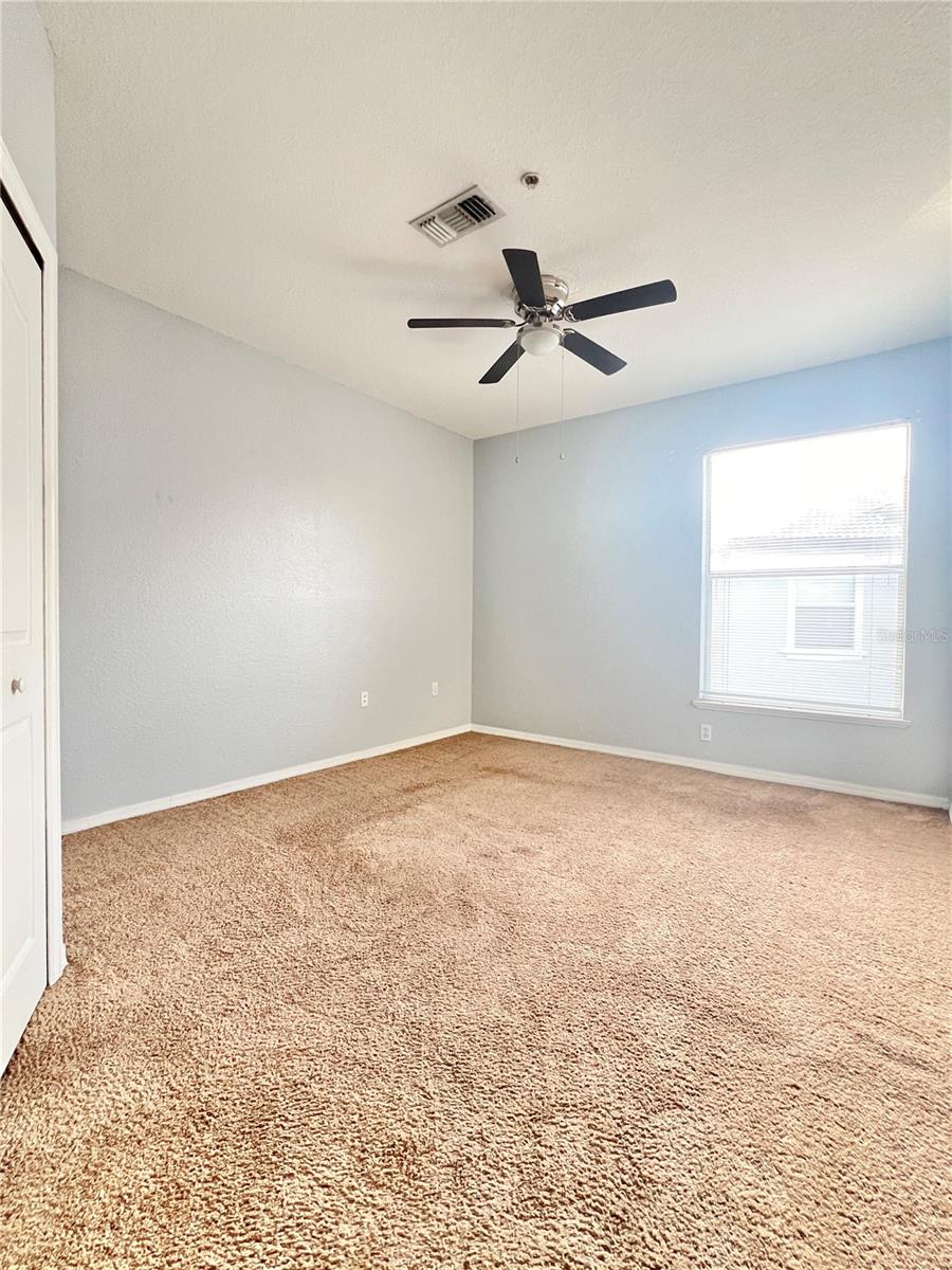 The bedroom has a lighted ceiling fan and window blinds.