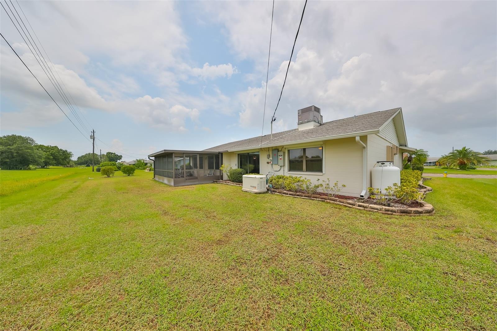 Rear view of home showing WHOLE HOUSE GENERATOR and (2) LARGE propane tanks on the side of the house.