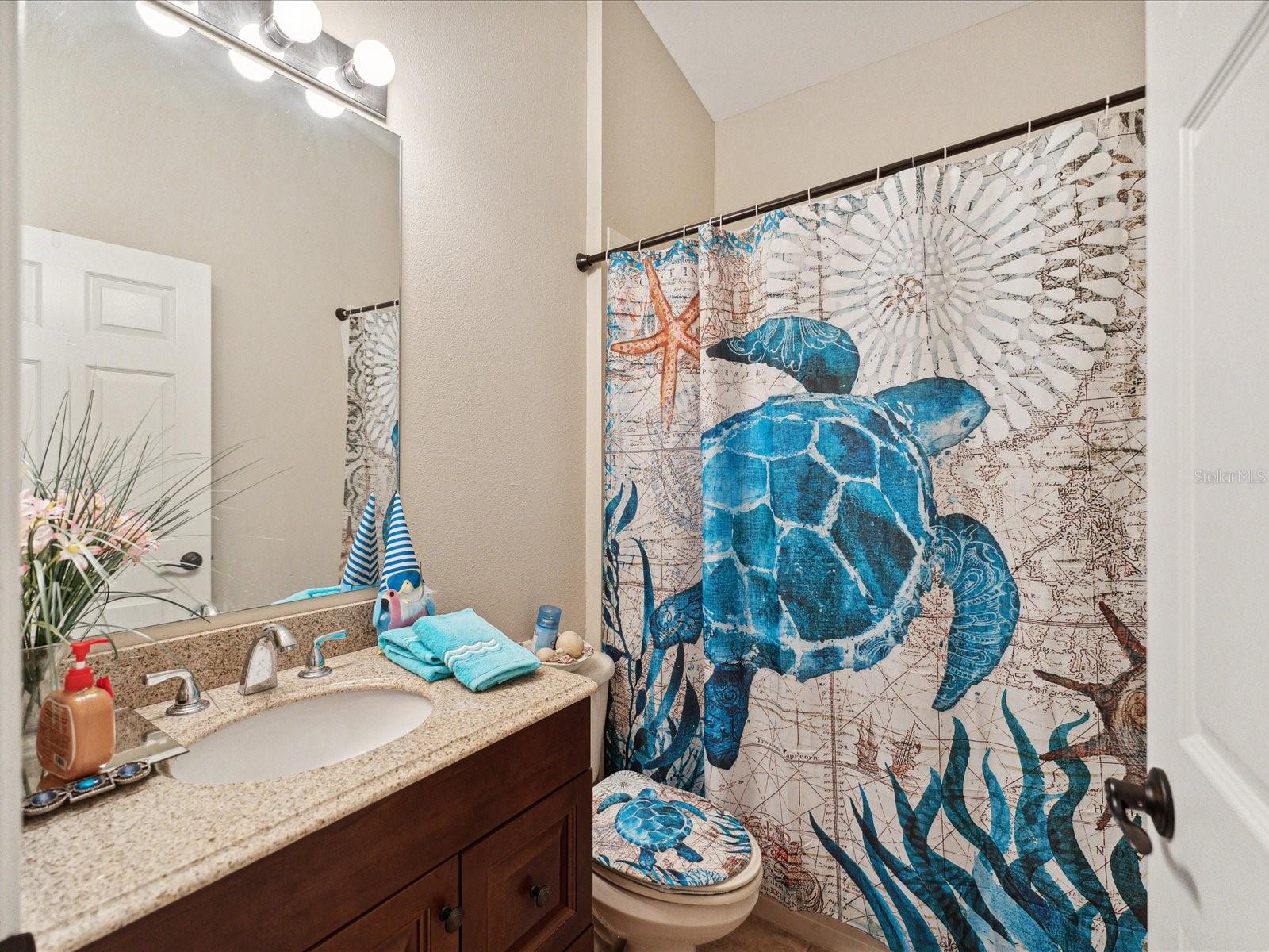 This bathroom features beveled edge granite countertops and cabinetry with updated hardware. The shower is a shower/tub combination.