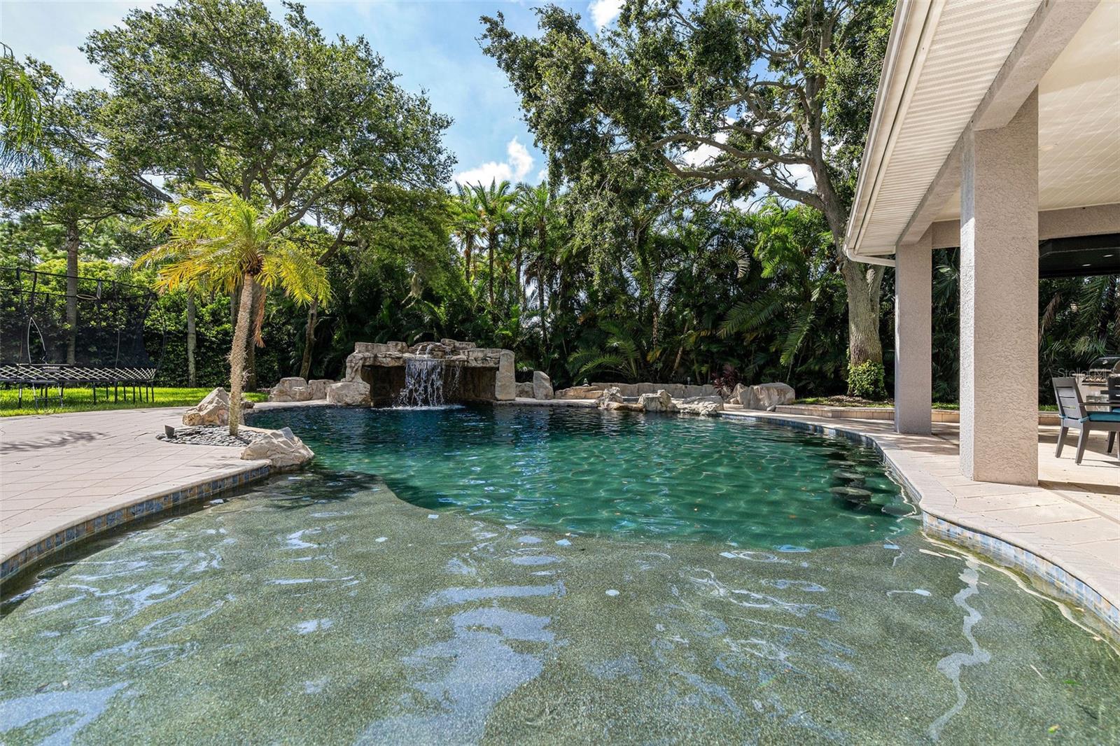 Baja shelf leading into pool with a. custom waterfall on back side of pool