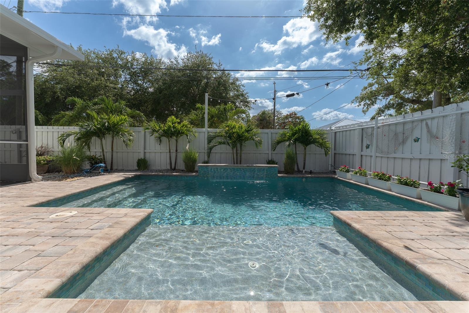 Pool with water features. Waterfall along with water feature on splash pad. Umbrella holder installed.