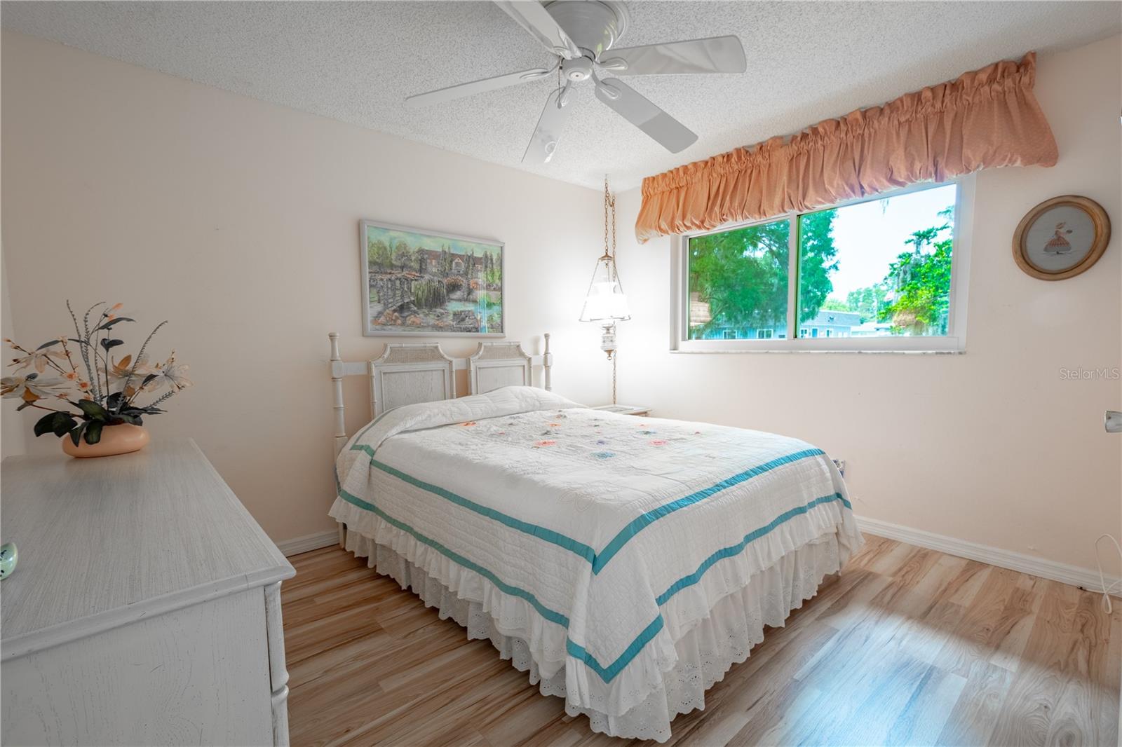 Bedroom Two features neutral tones, a wood laminate floor, a ceiling fan and a walk-in closet.