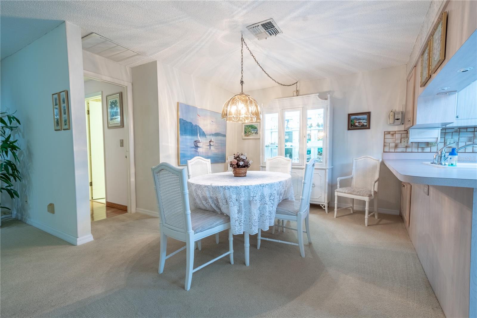 The dining room is open to the living room and kitchen and features neutral tones and plush carpet.