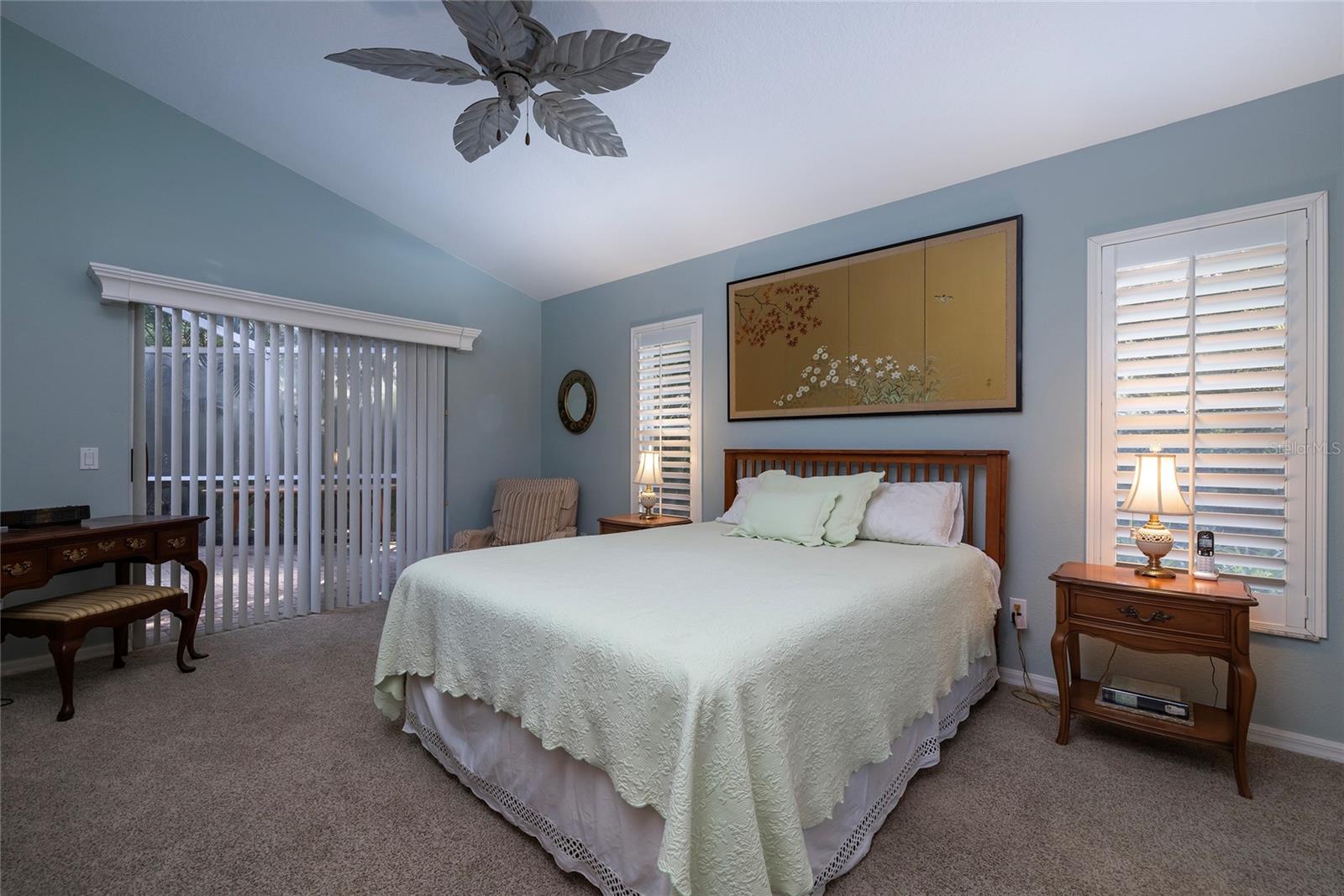 Primary bedroom with plantation shutters and patio access