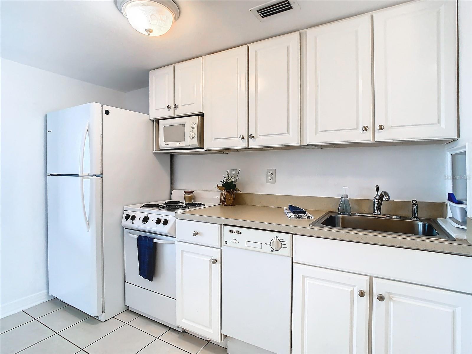 Your back is to the lavatory, view towards the kitchenette. (To the right is the HVAC closet with some extra storage space) Entrance door, out of view, to your right. That is a newer fridge. Cabinets have had a fresh coat of paint, too. Notice there is even a dishwasher???