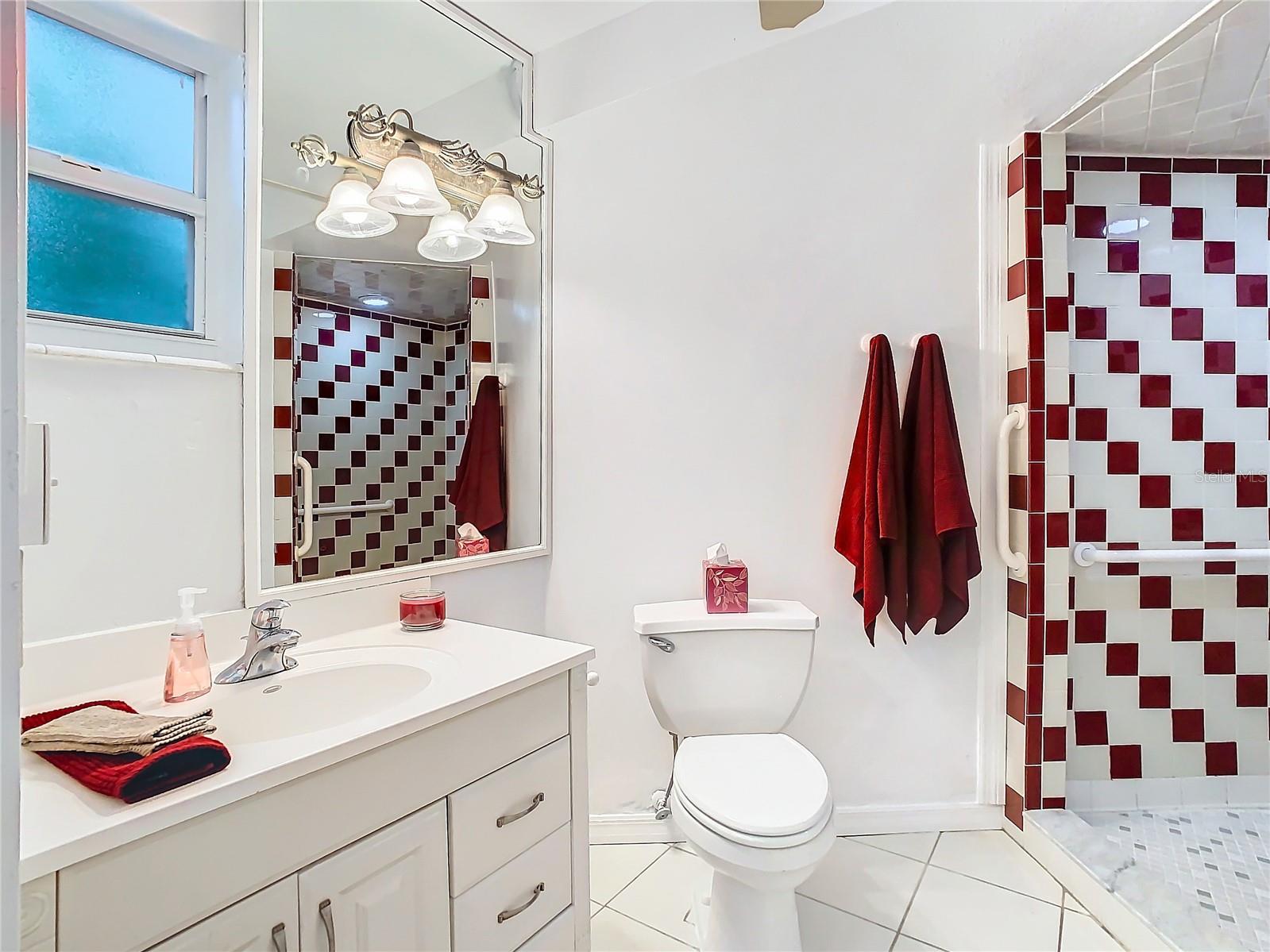 Closer view of the vanity, commode & mint condition retro shower. To your right is a large closet.