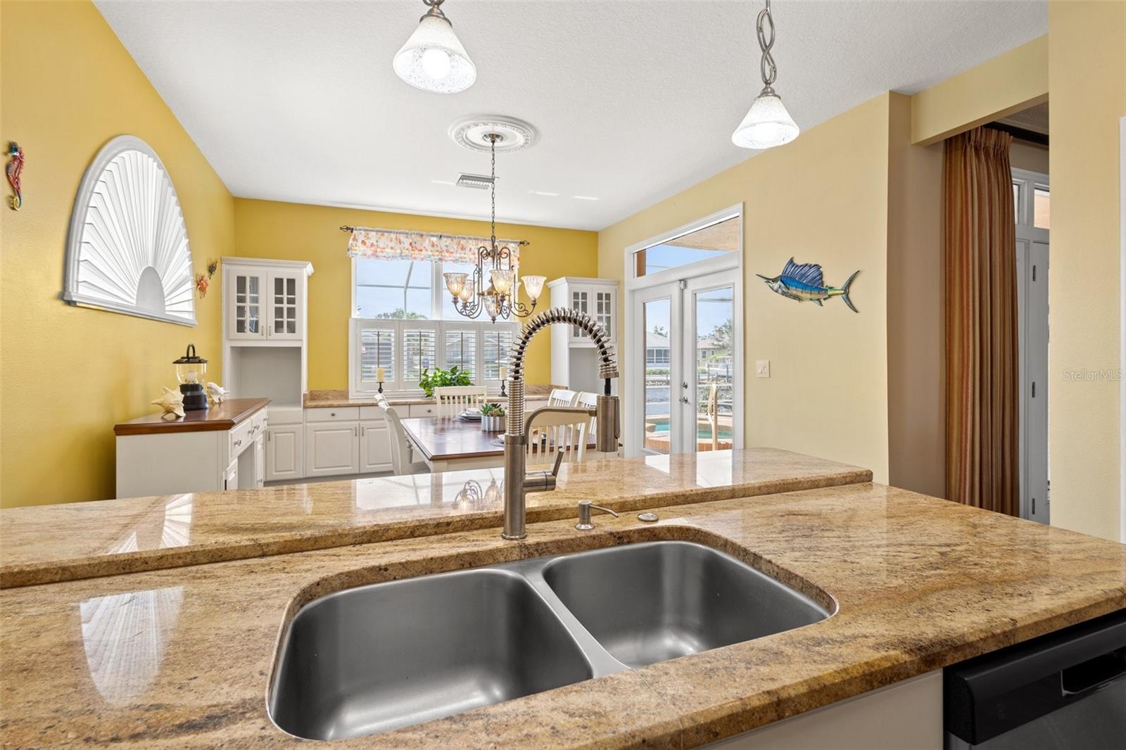 View from kitchen to Dinette area, pool and water.