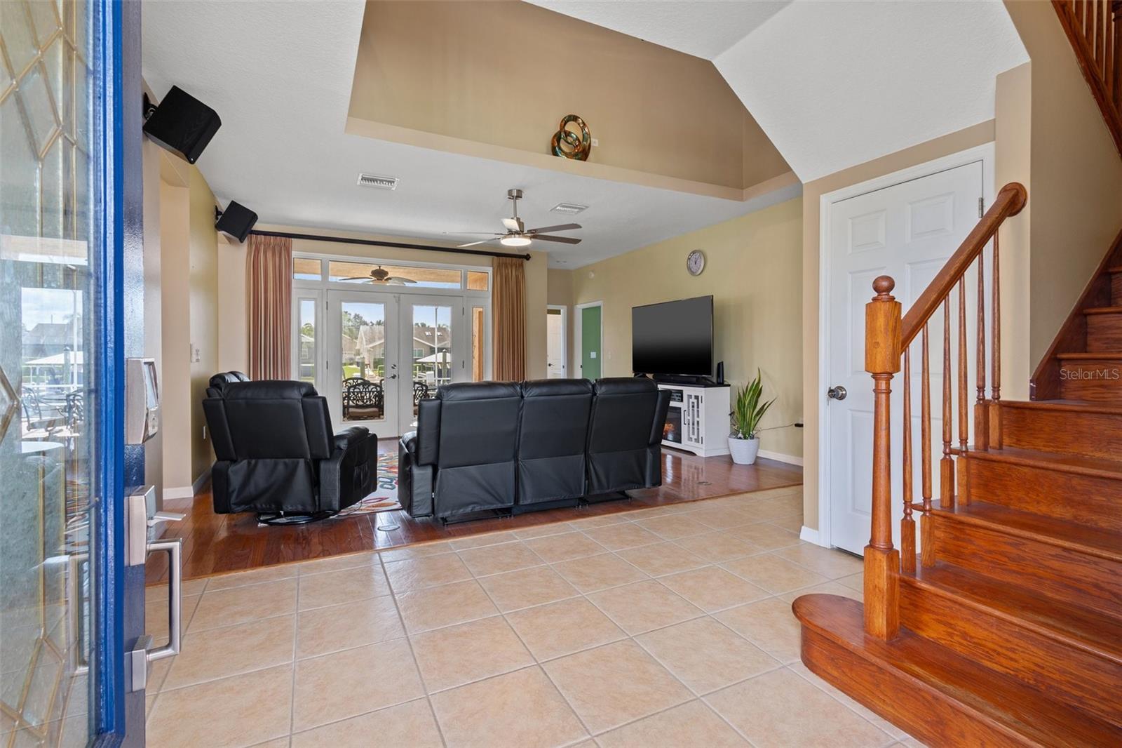 Entry into living area with view to the pool and water.  Primary bedroom and bonus area up the stairs to the left