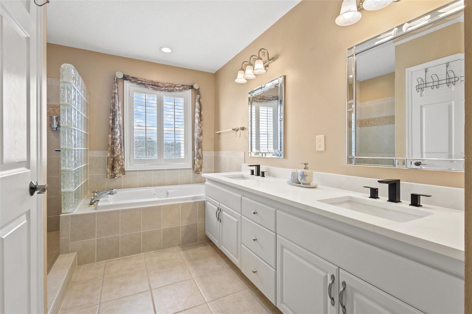 beautiful primary bathroom with dual vanities, jet tub and walk-in shower.