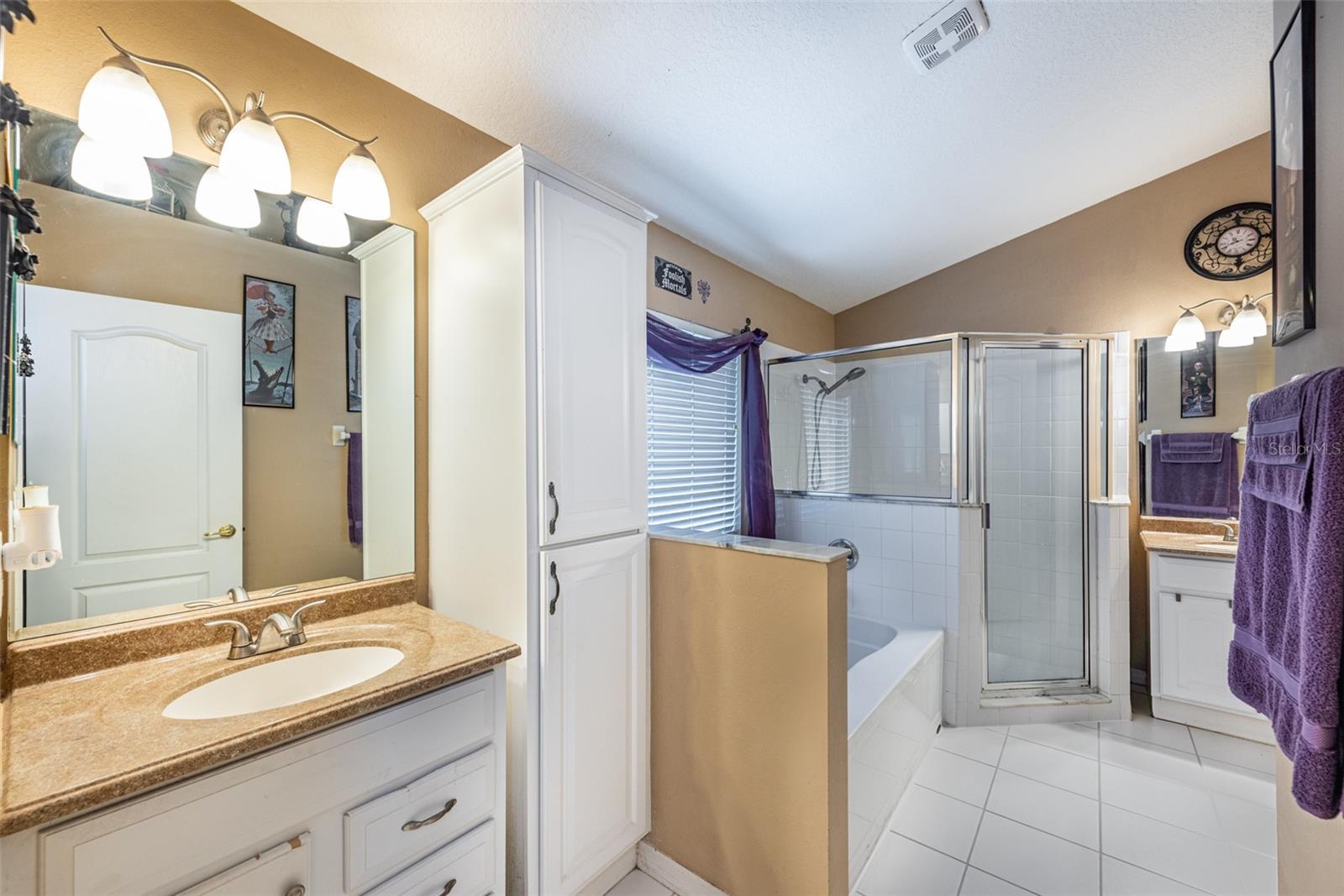 Primary en suite retreat with separate vanities with sinks, a soaking tub, and a large shower.