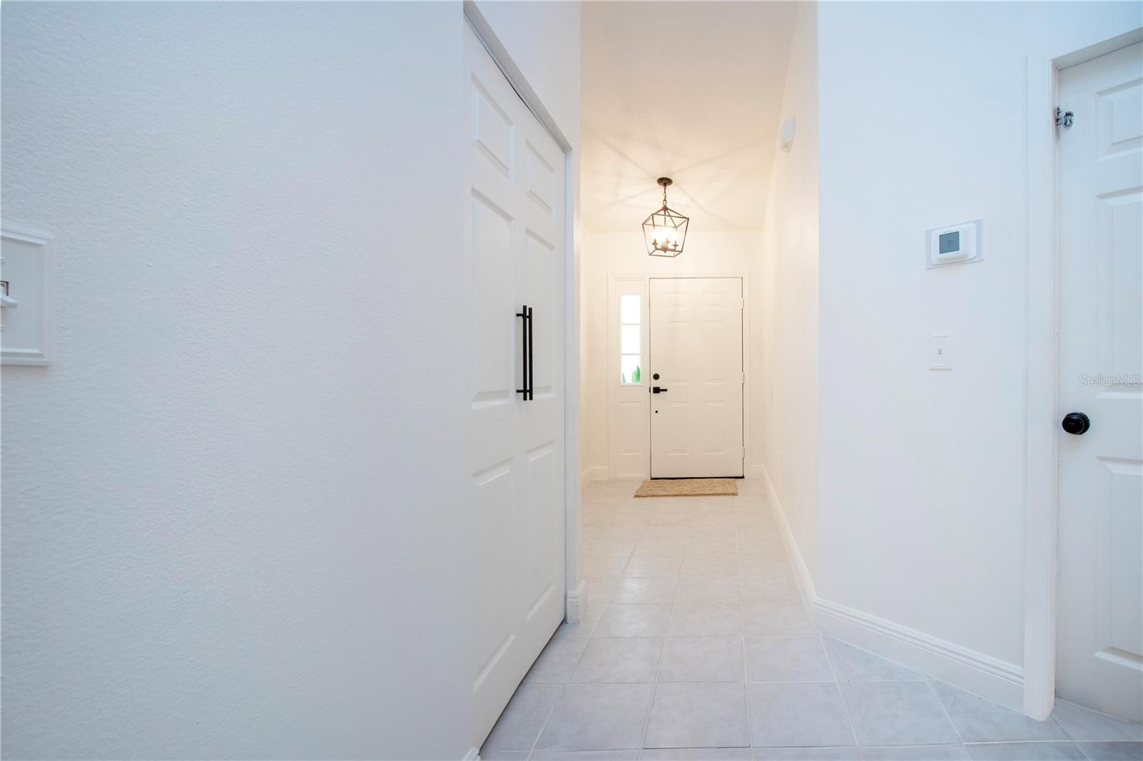 Hallway to the front door coat closet to the left and door to the garage is to the right