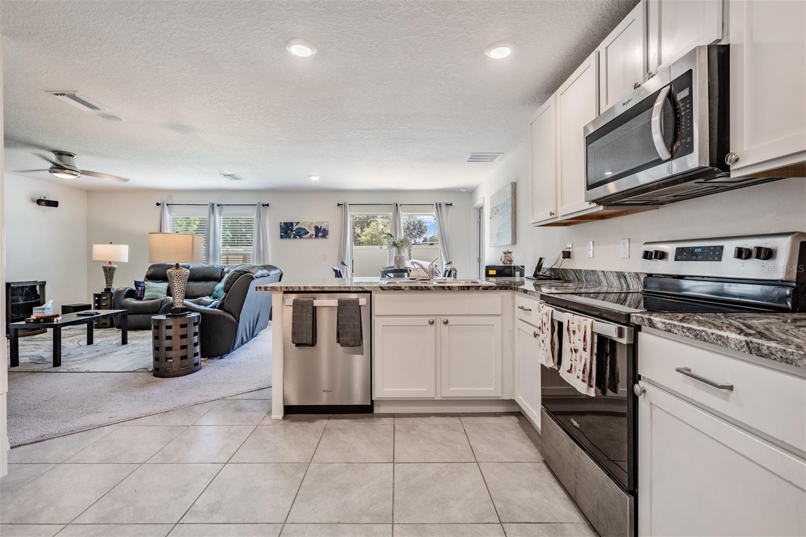 Large and open kitchen with tile flooring, inset lighting, double door pantry and stainless steel appliances