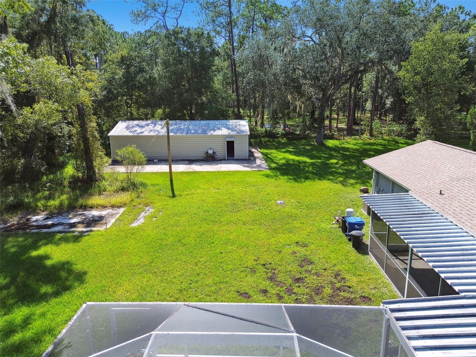 View of backyard and 1500 sf shop with attached slab for RV or basketball perhaps