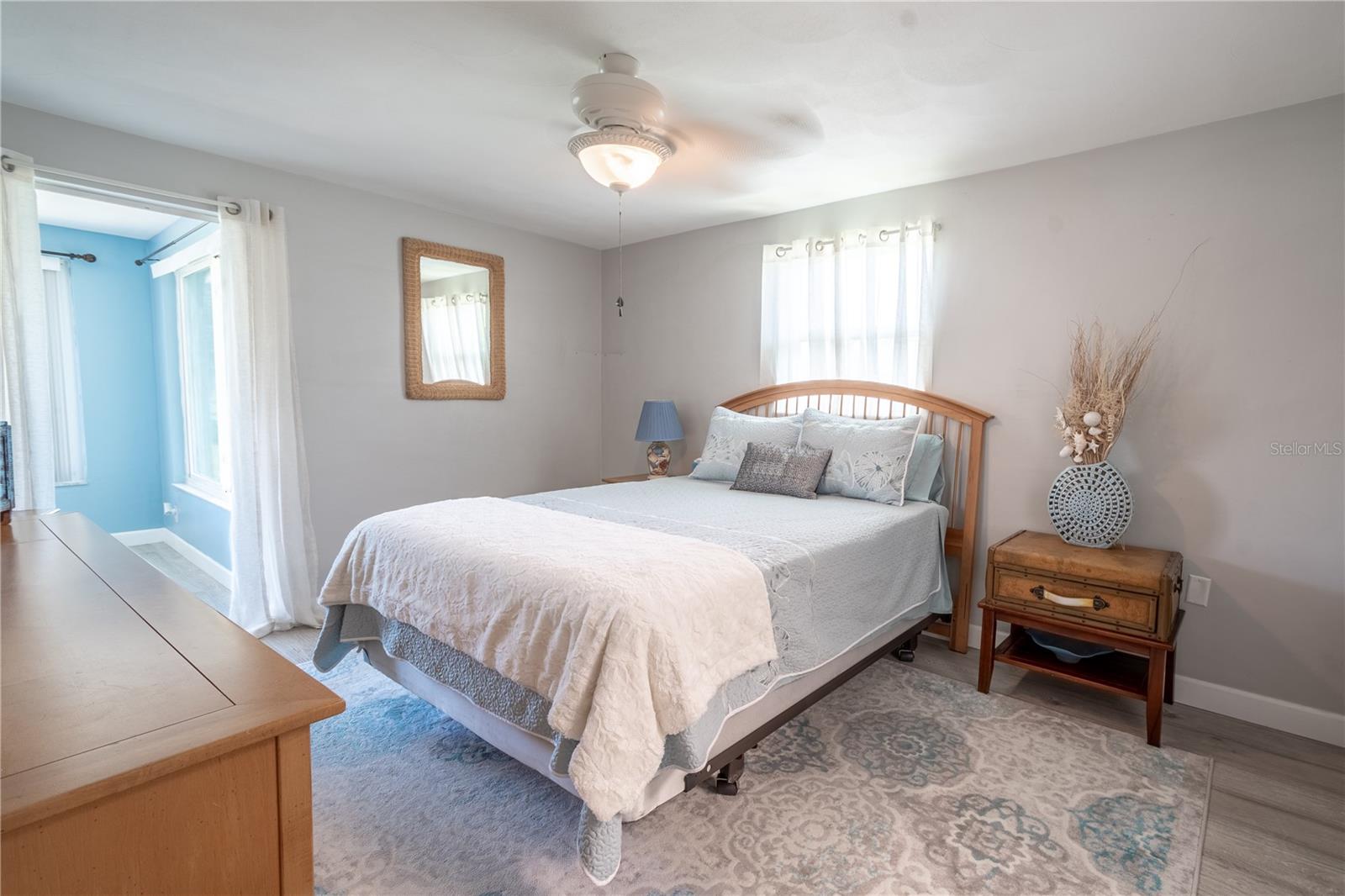 The primary bedroom is bathed in neutral tones, wood laminate flooring and a decorative ceiling fan with light kit.