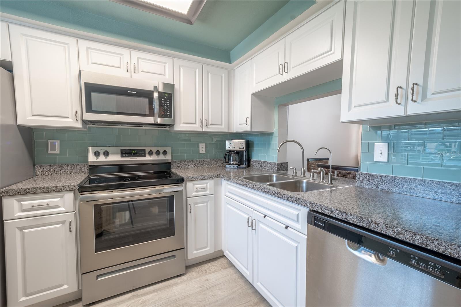 The kitchen features an abundance of cabinets, glass subway tile backsplash, and granite countertops.