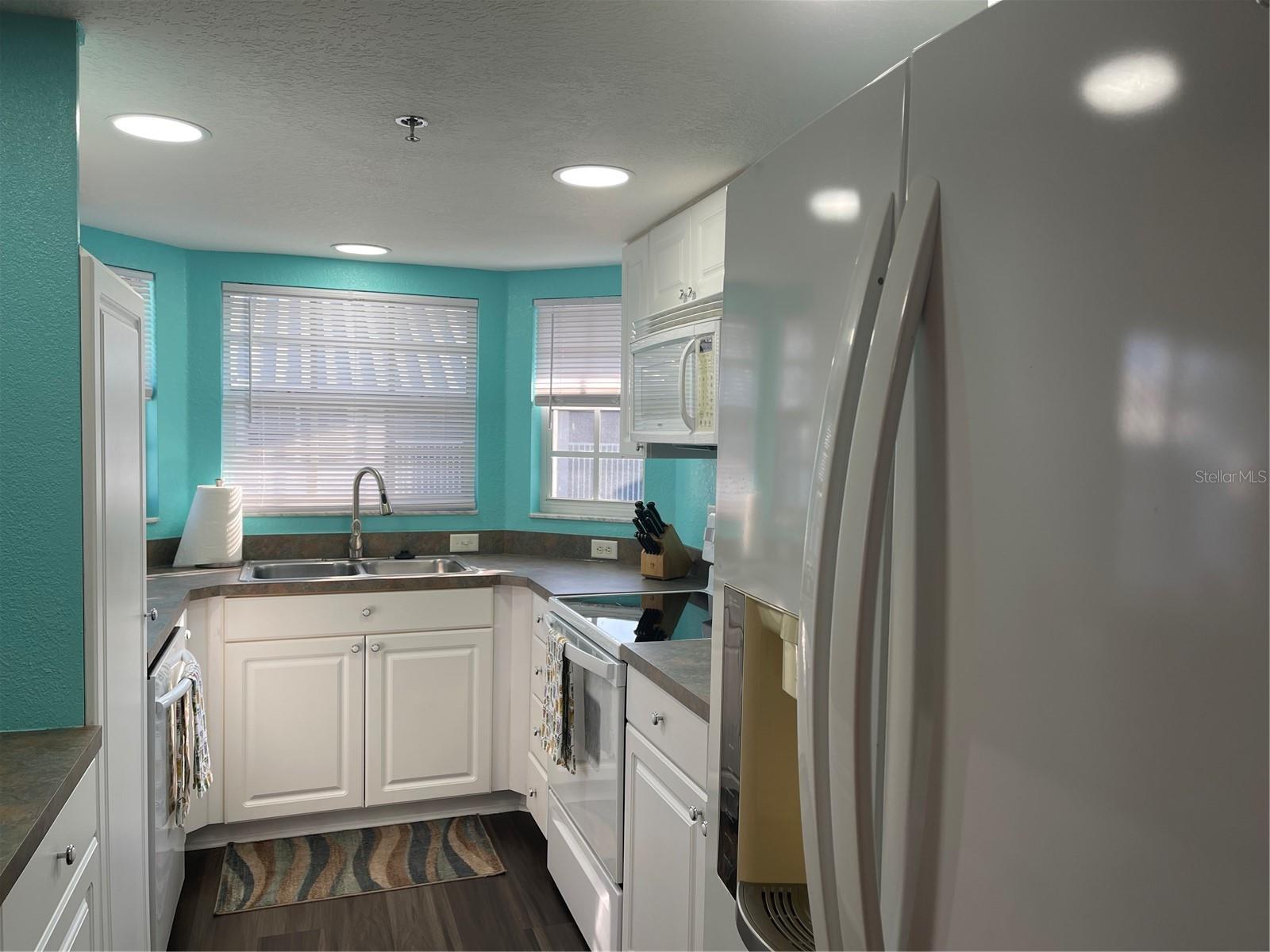 four windows in kitchen welcome sunshine and provide ventilation while cooking.