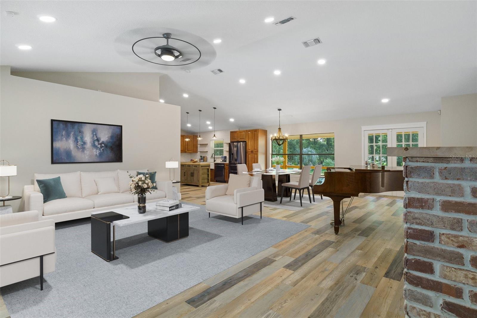 Virtually staged living room looking toward dining area and kitchen. Brick fireplace (electric) to the right.