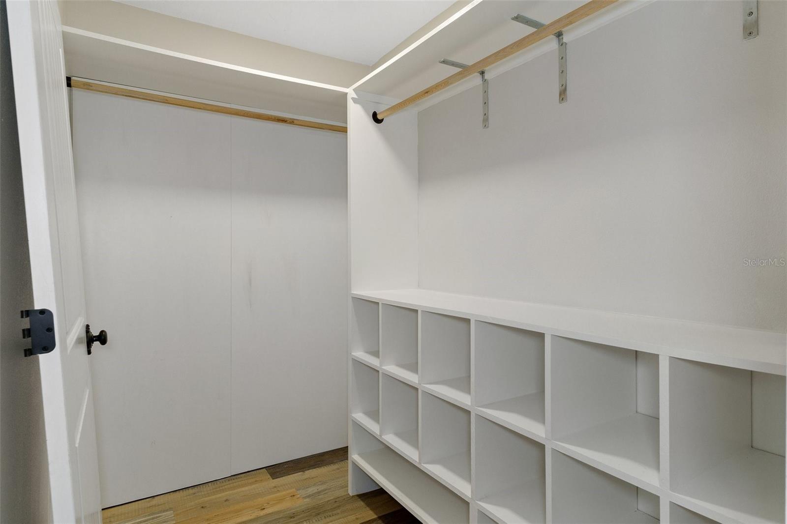 Primary closet with hidden storage behind back wall.