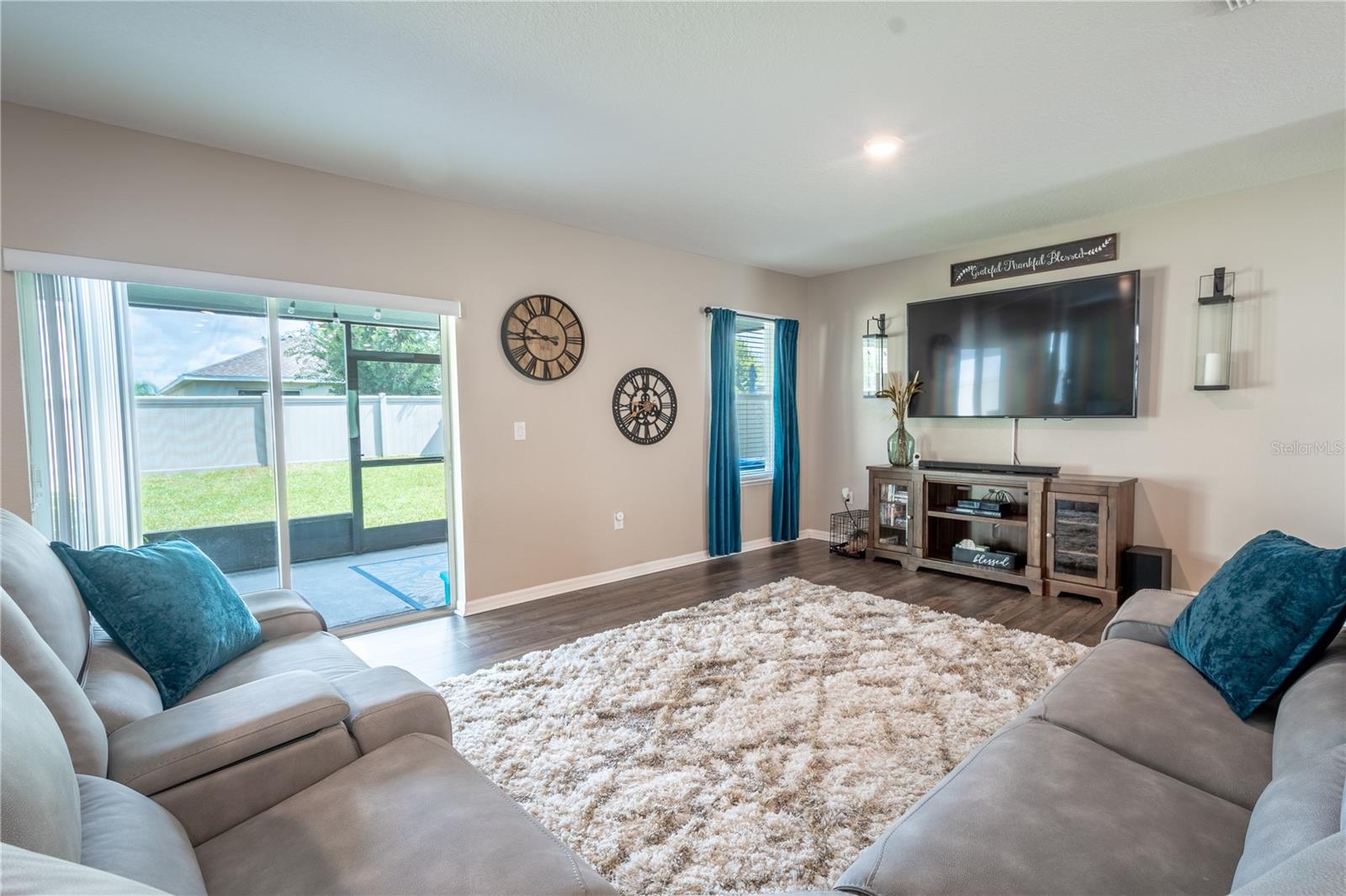 The living room features wood laminate flooring, a neutral color palette and sliding glass doors that lead to the screened in porch/lanai and private, fenced in back yard.