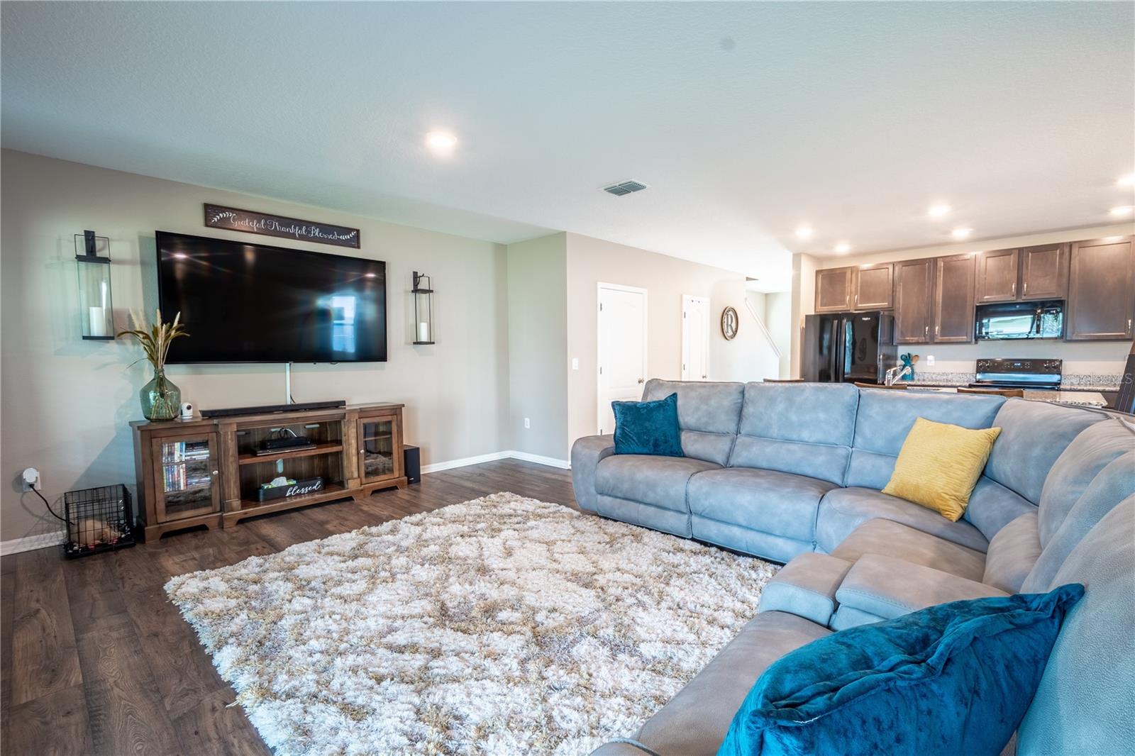 The living/family room features wood laminate flooring and is complemented with natural tones.