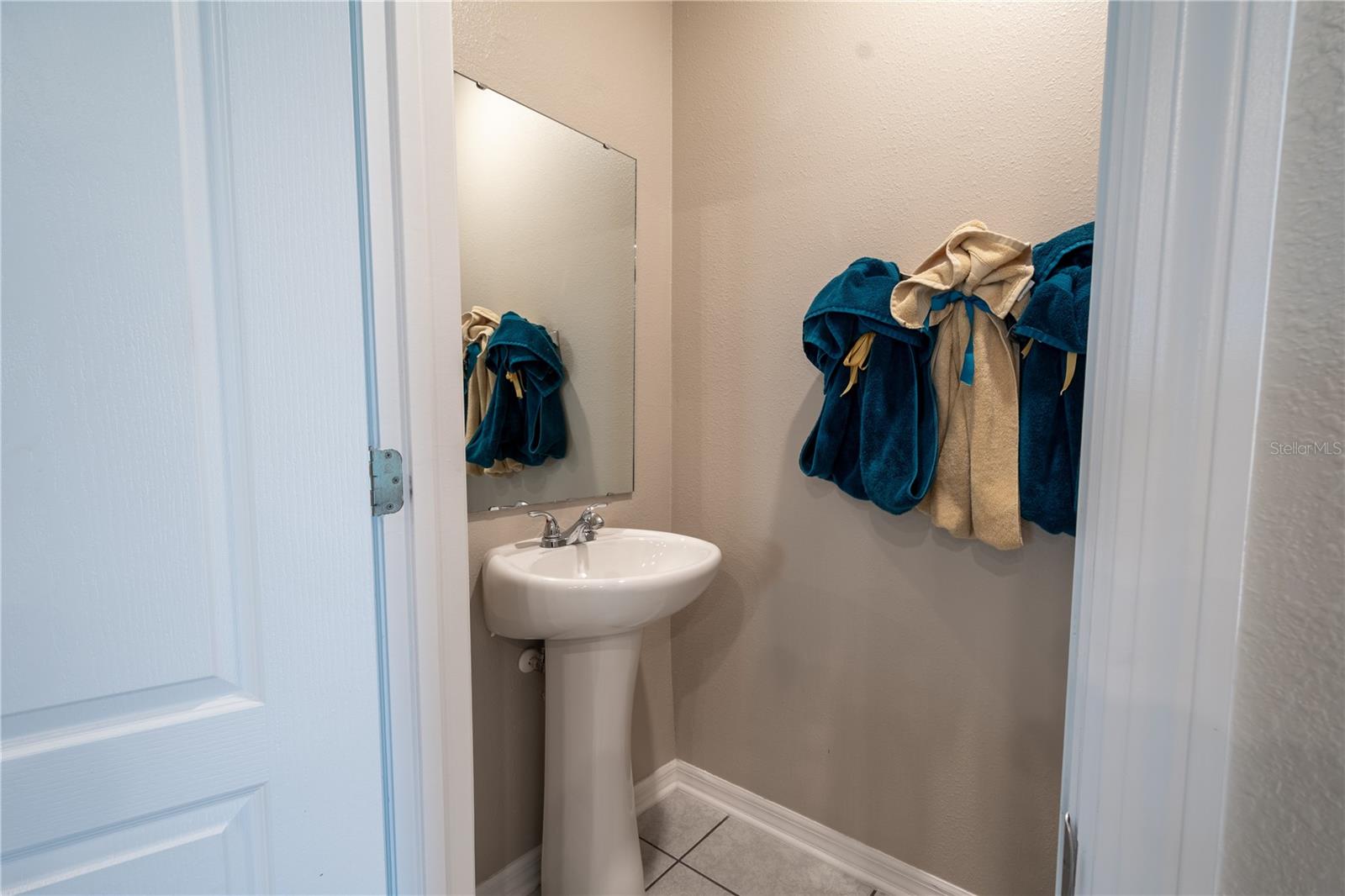 Downstairs half bathroom features ceramic tile flooring and a pedestal sink.