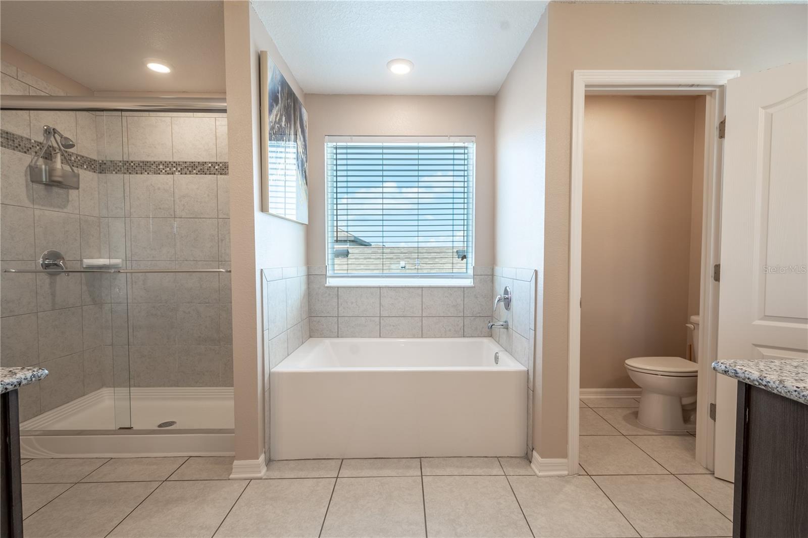 The primary ensuite features ceramic tile flooring, a private water closet, a garden tub and a glass enclosed, walk-in shower.