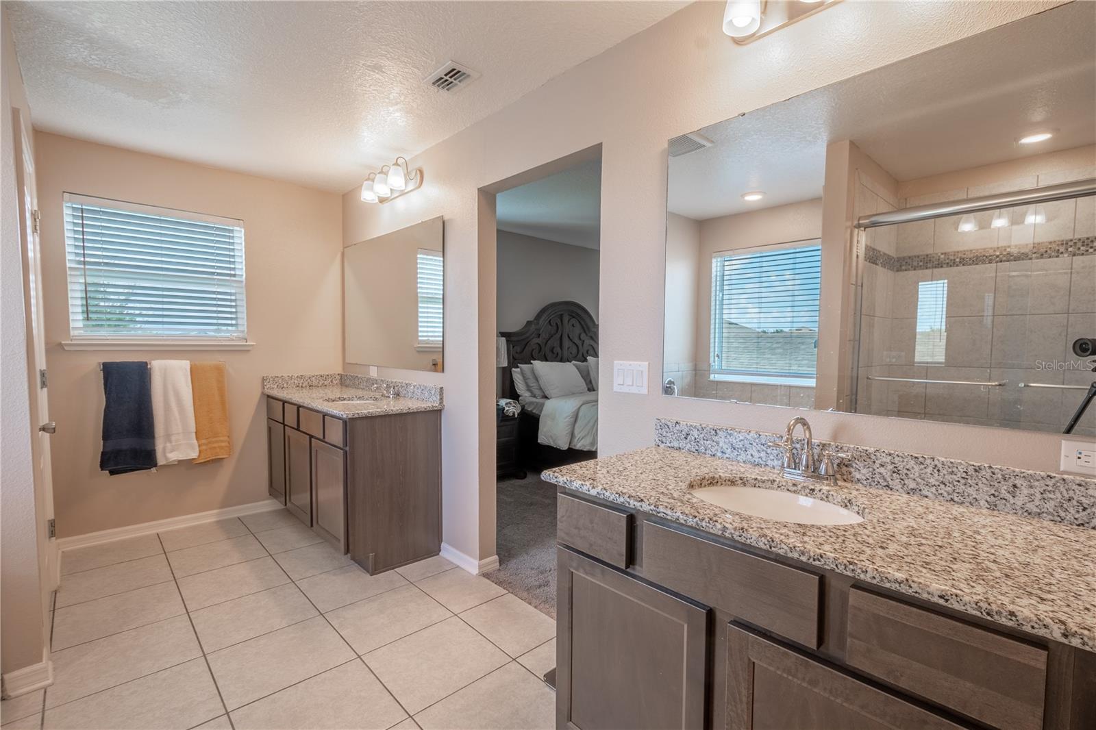 The primary ensuite features 2 mirrored wood vanities with storage, granite counters and downlight fixtures.