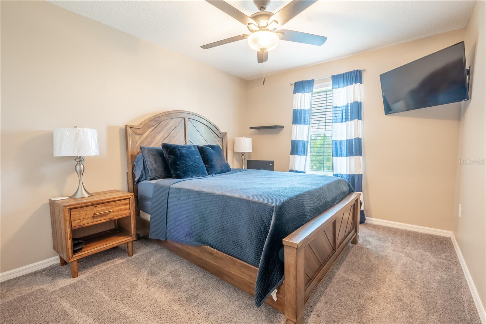 Bedroom two features plush neutral toned carpet, a built-in closet and a ceiling fan with light kit.