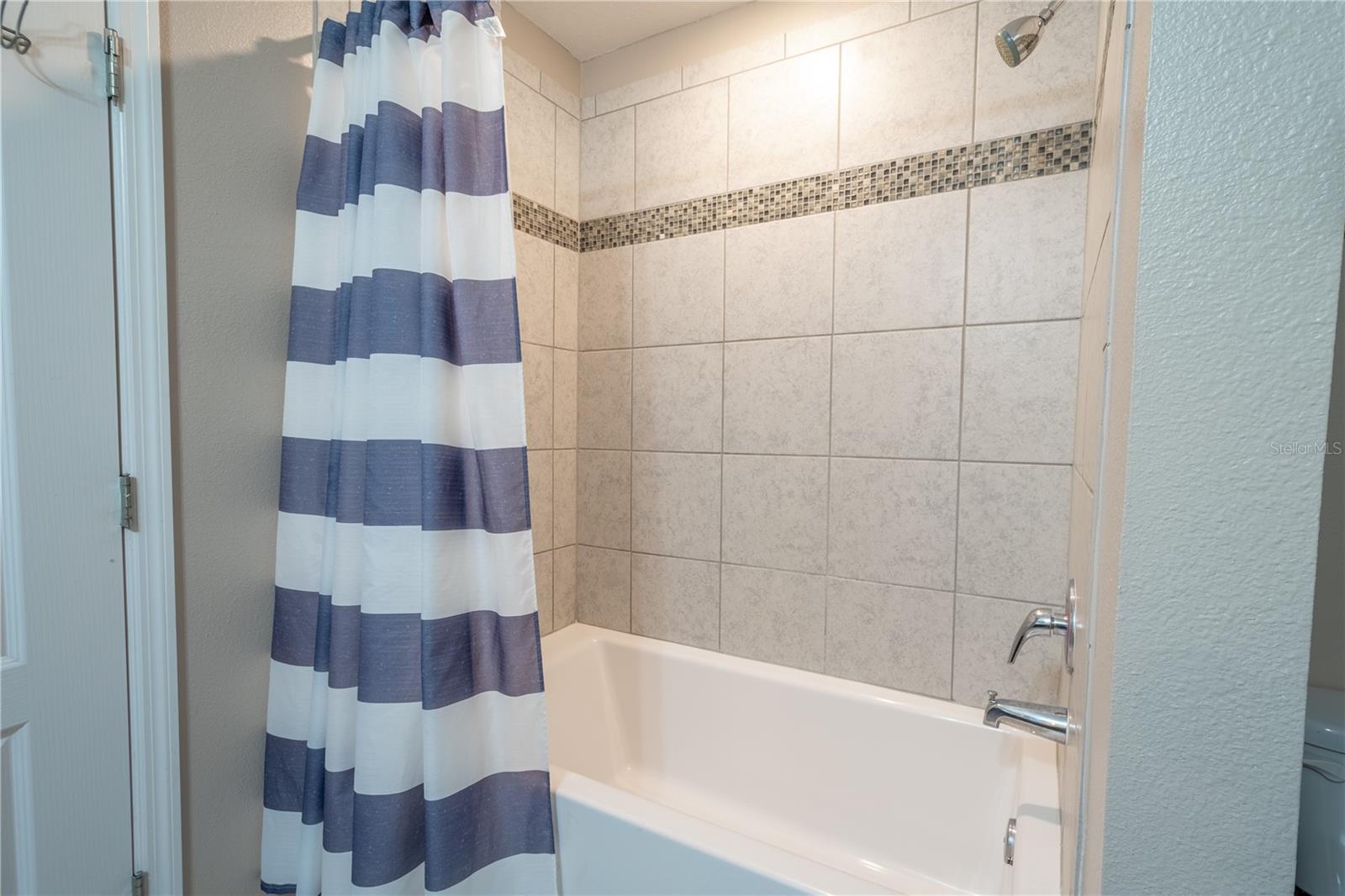 Bathroom Three features a tiled tub with shower.