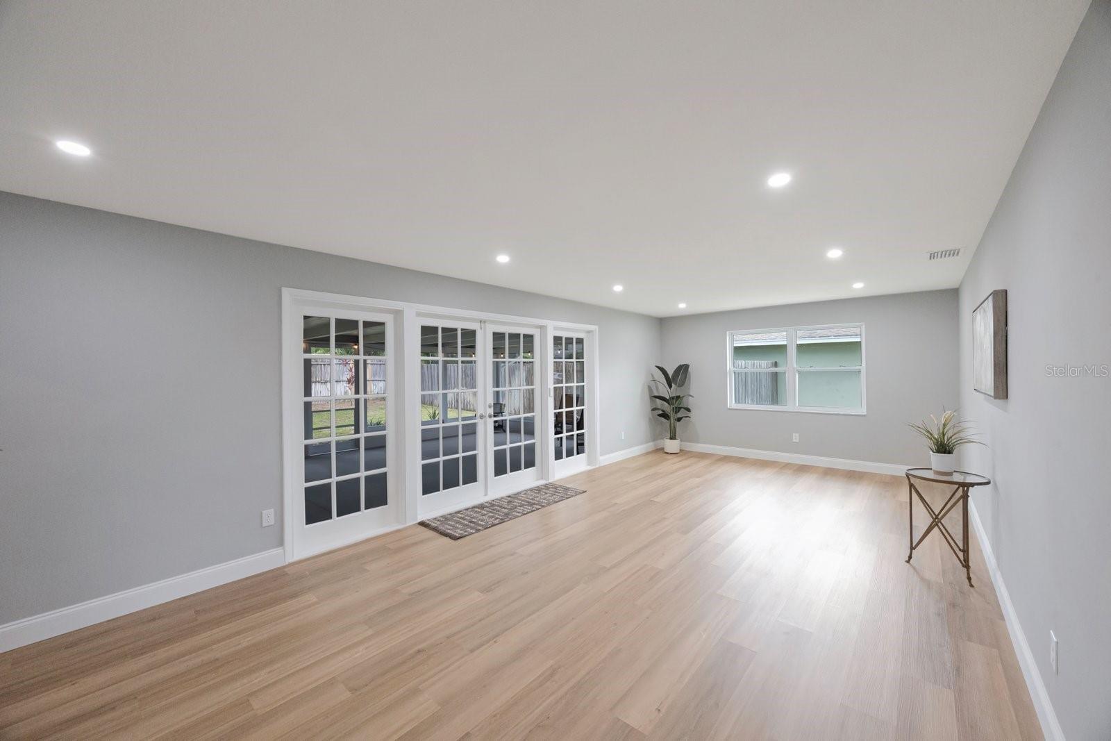 Gorgeous living room with recessed lighting and french doors opening to the massive screened lanai!