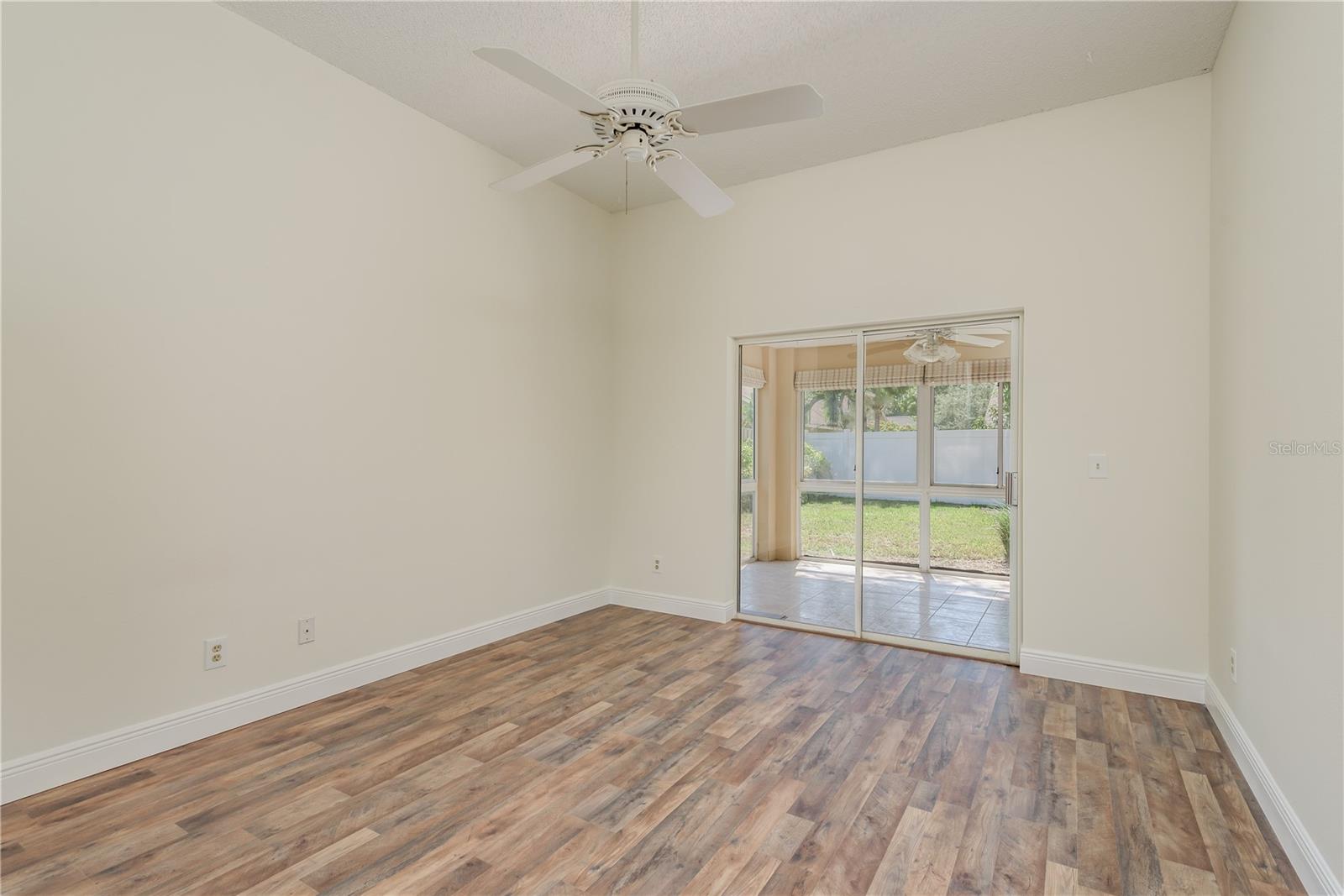 Primary bedroom with ceiling fan and sliding doors to Florida room