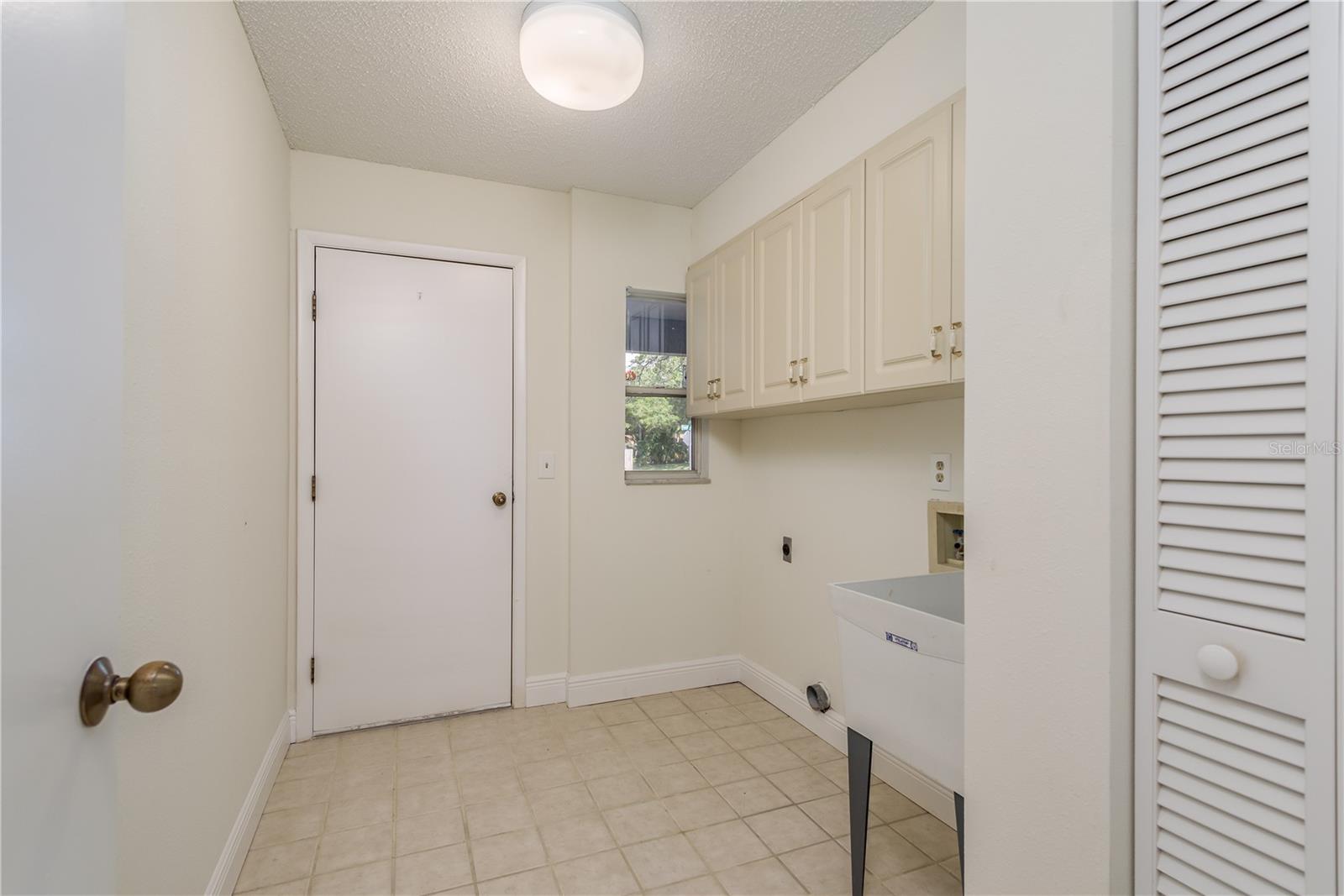 Laundry room with storage pantry, utility sink and cabinets