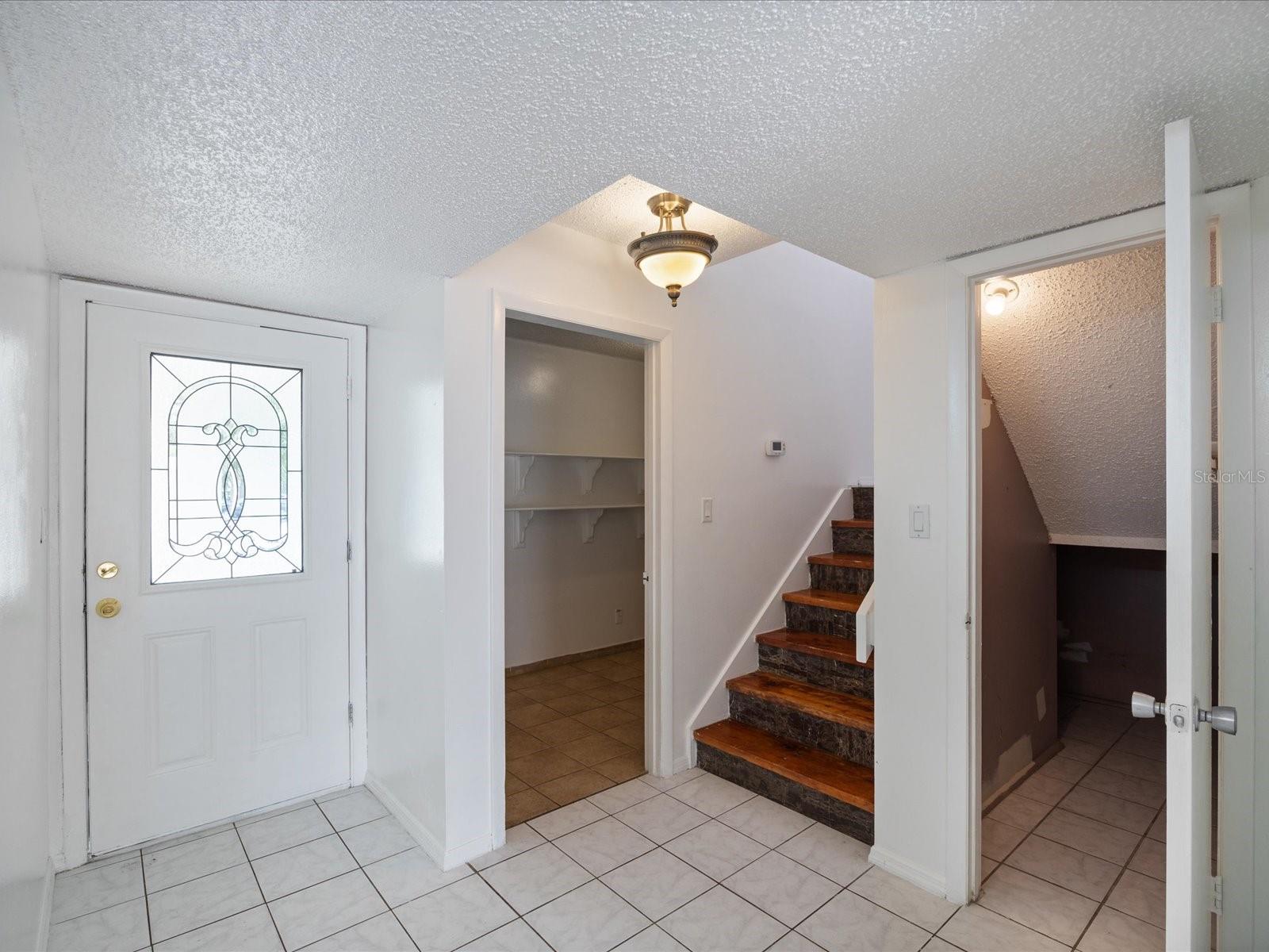 Front entryway looking at stairway, laundry room & under stair storage closet