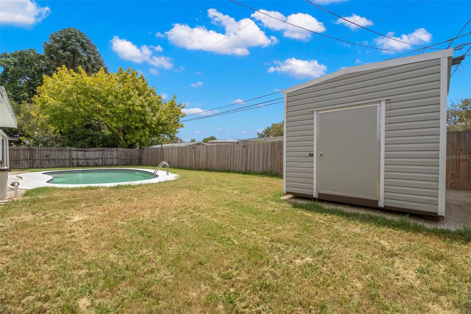 Backyard with chlorine, in-ground pool, and shed.