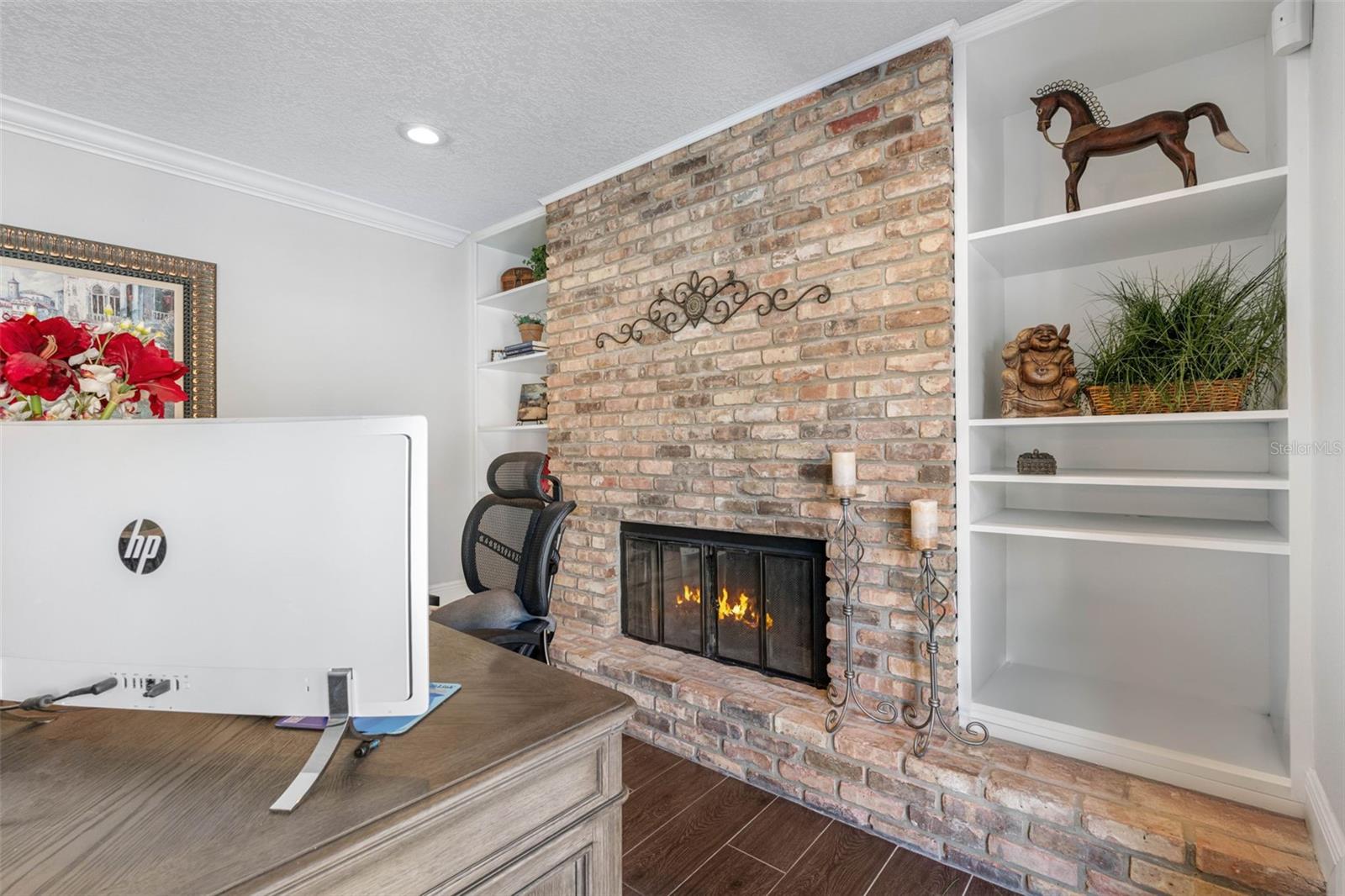 Charming room with an exposed brick wall, cozy fireplace, and ample shelving.