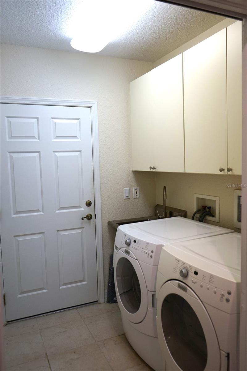 laundry room has cabinets and a closet with the AC and water tank, door goes to garage