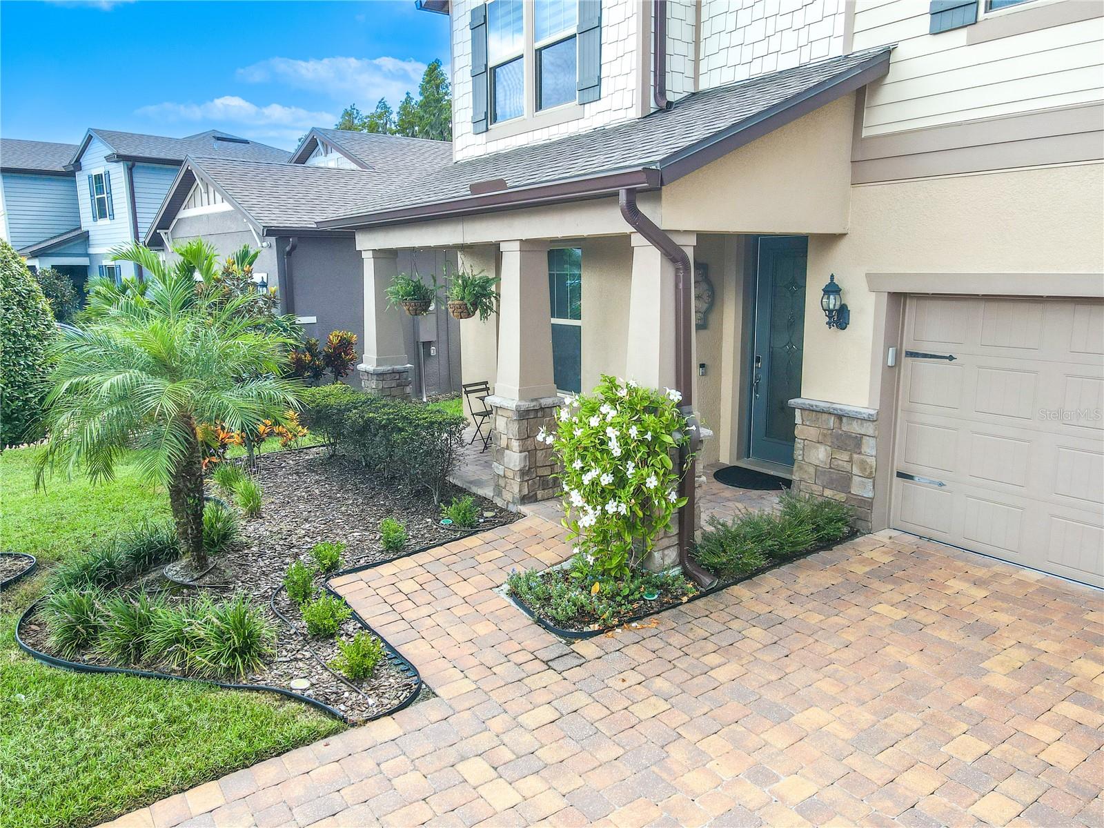 Pavered driveway and walkway, landscaped entryway and covered front porch.