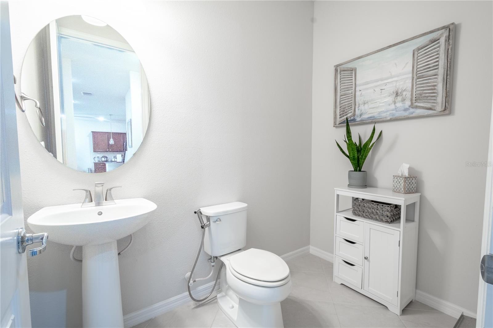 The downstairs powder room features a pedestal sink with a downlight fixture, mirror, and ceramic tile flooring.