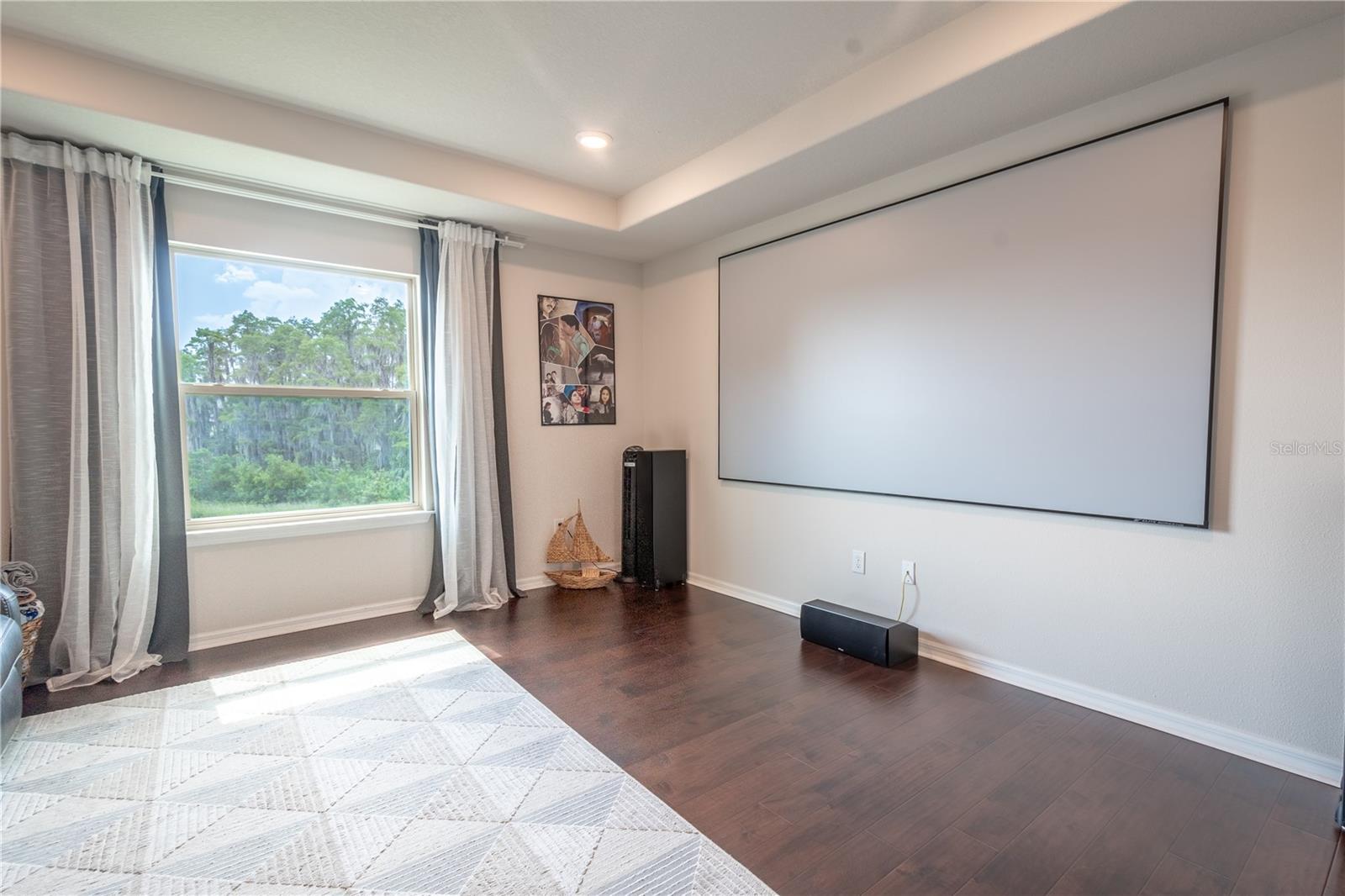 The loft features rich wood laminate flooring, a tray ceiling with recessed lighting and a neutral color palette.