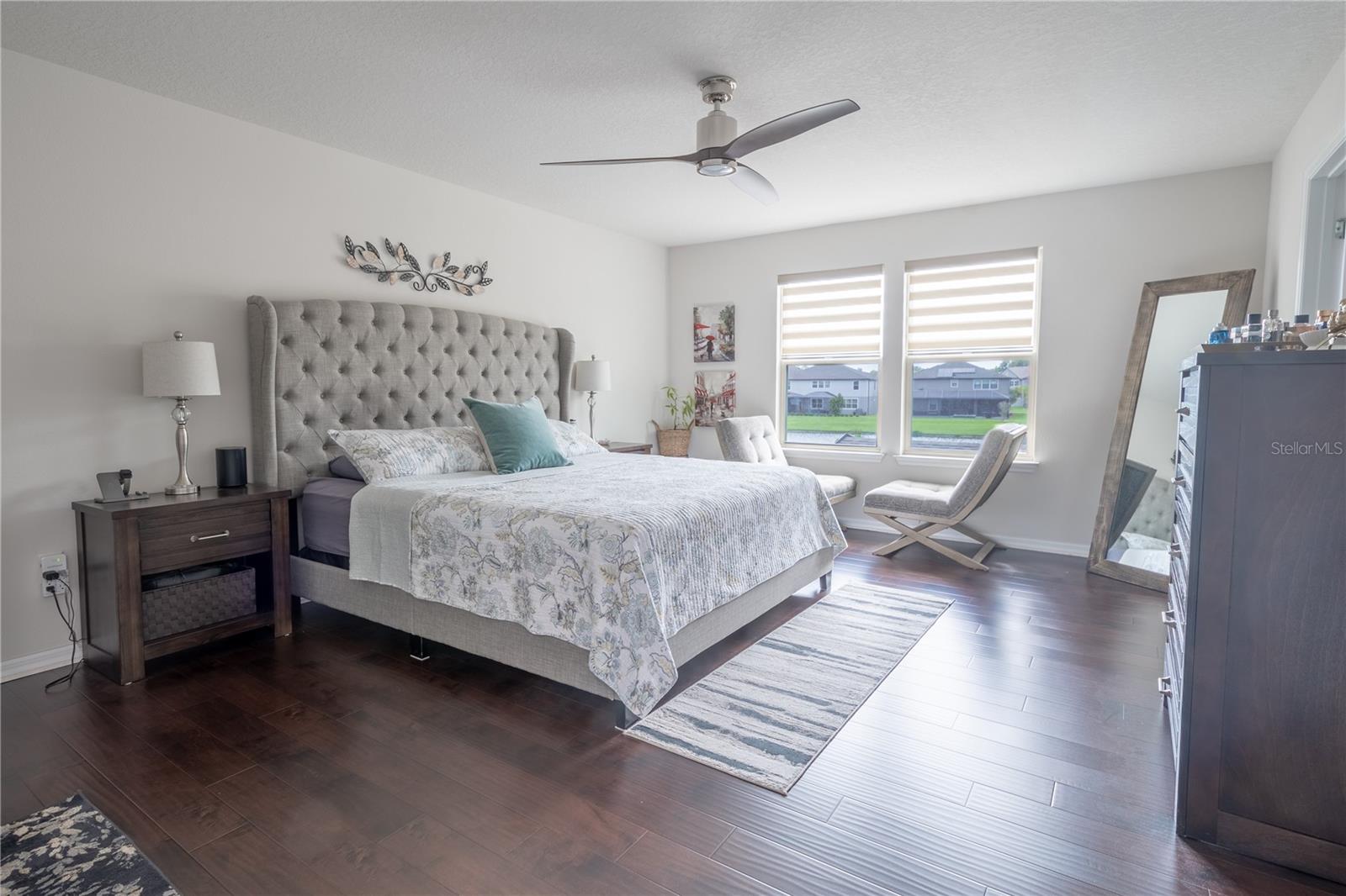 Primary bedroom features wood laminate flooring, a ceiling fan with light kit, a walk-in closet and ensuite bath.