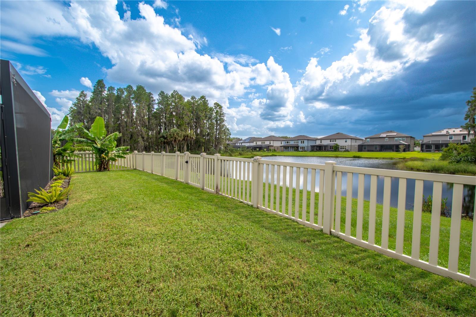 The yard has a vinyl fence and a view of the pond.