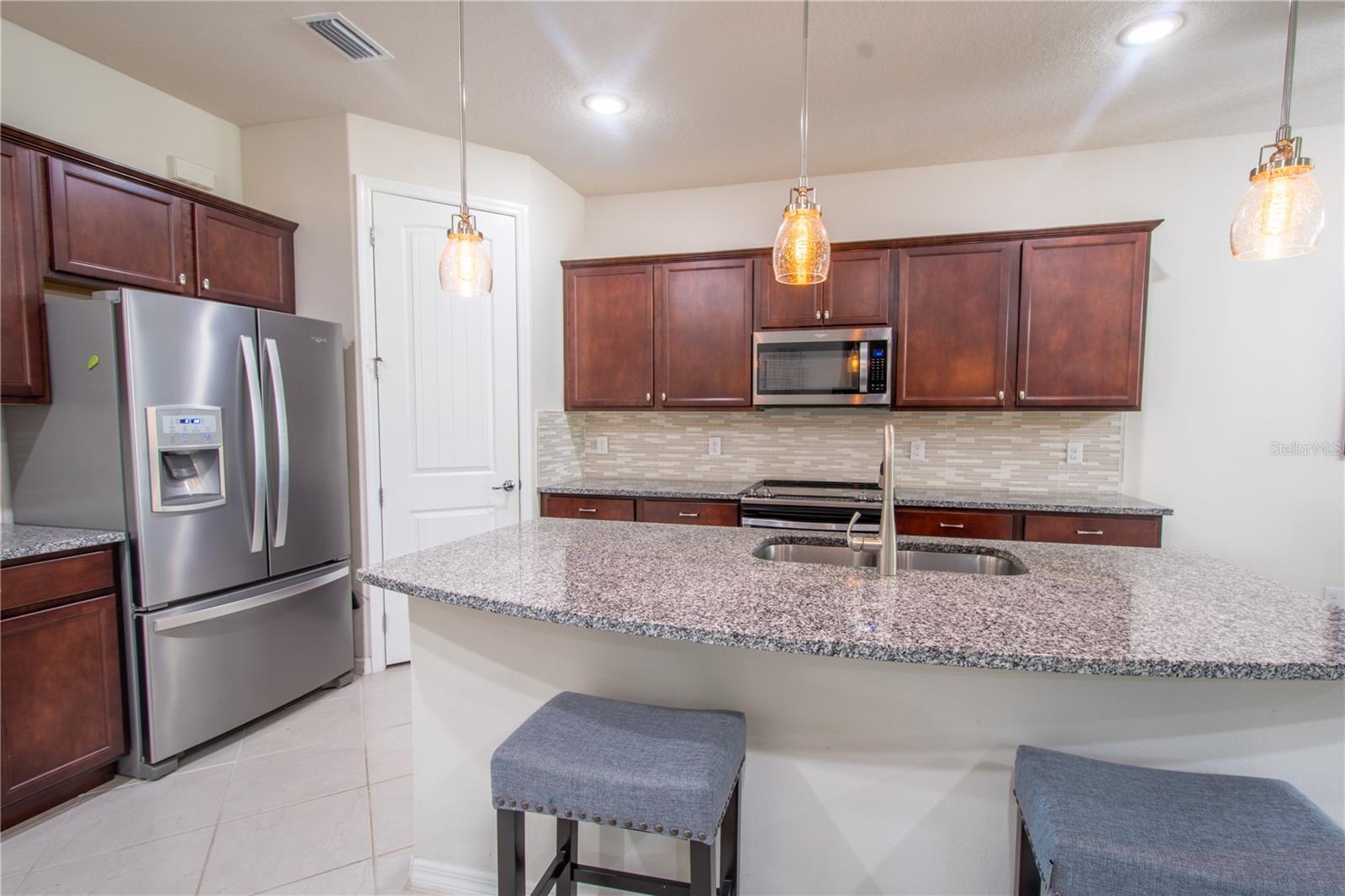 Three artistic glass pendant lights hang above the breakfast bar