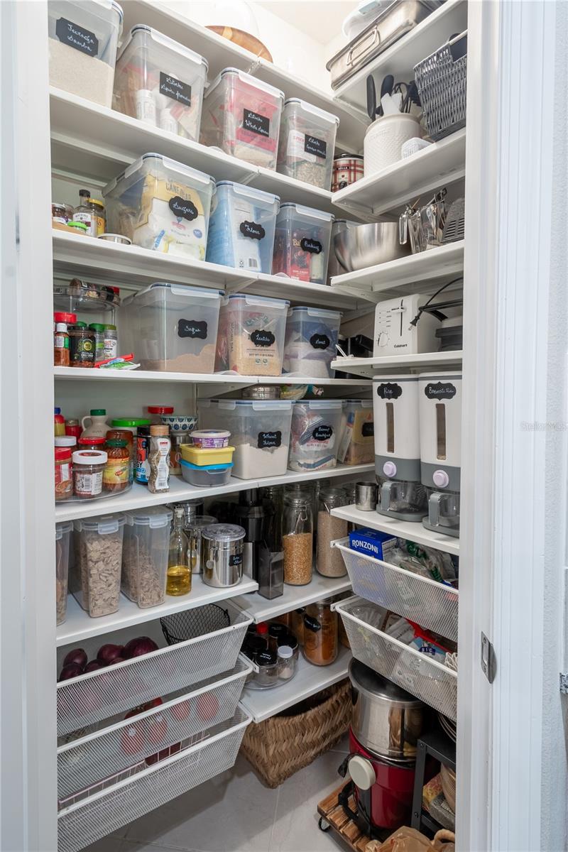 A well-organized walk-in pantry with built-in shelving and pull-out drawers.