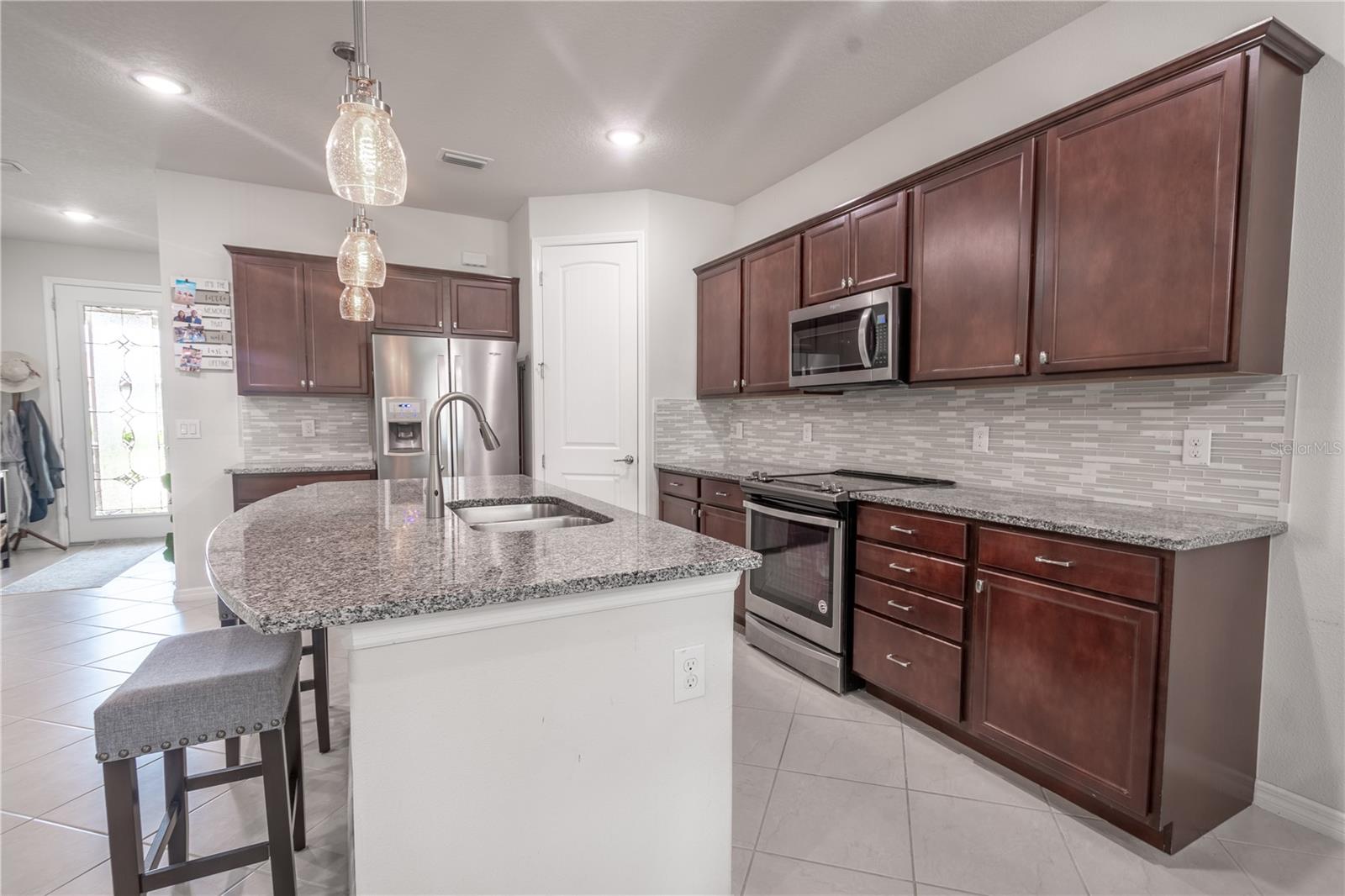 The kitchen features rich wood cabinetry, granite counters, a full suite of GE stainless steel appliances (2019)