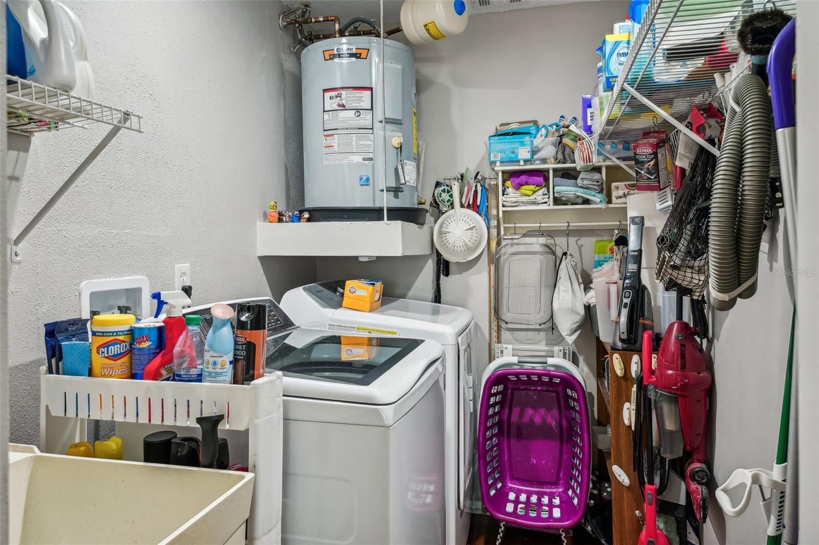 Inside laundry room with utility sink, shelving and houses hot water tank and electrical panel.