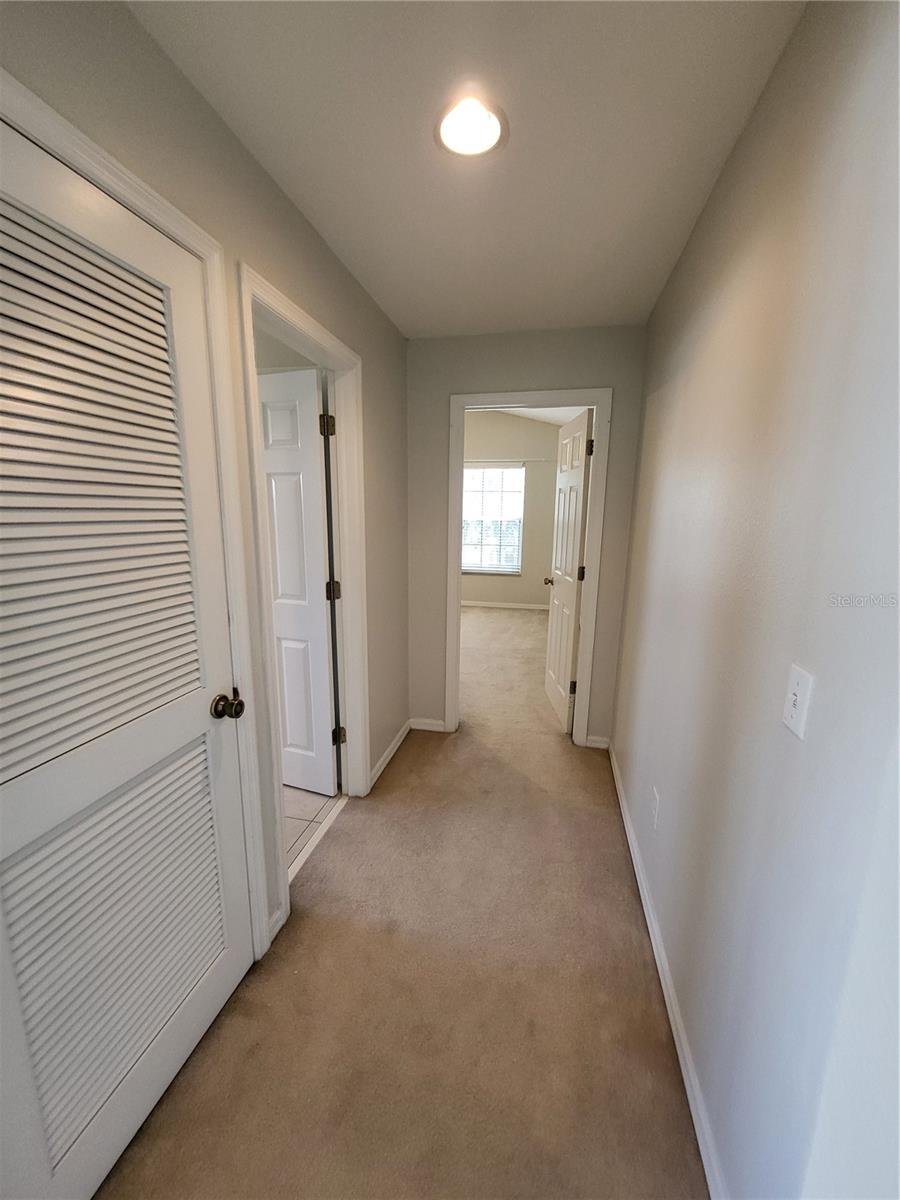 Hallway to front bedroom with bathroom on left.  Closed door is AC closet